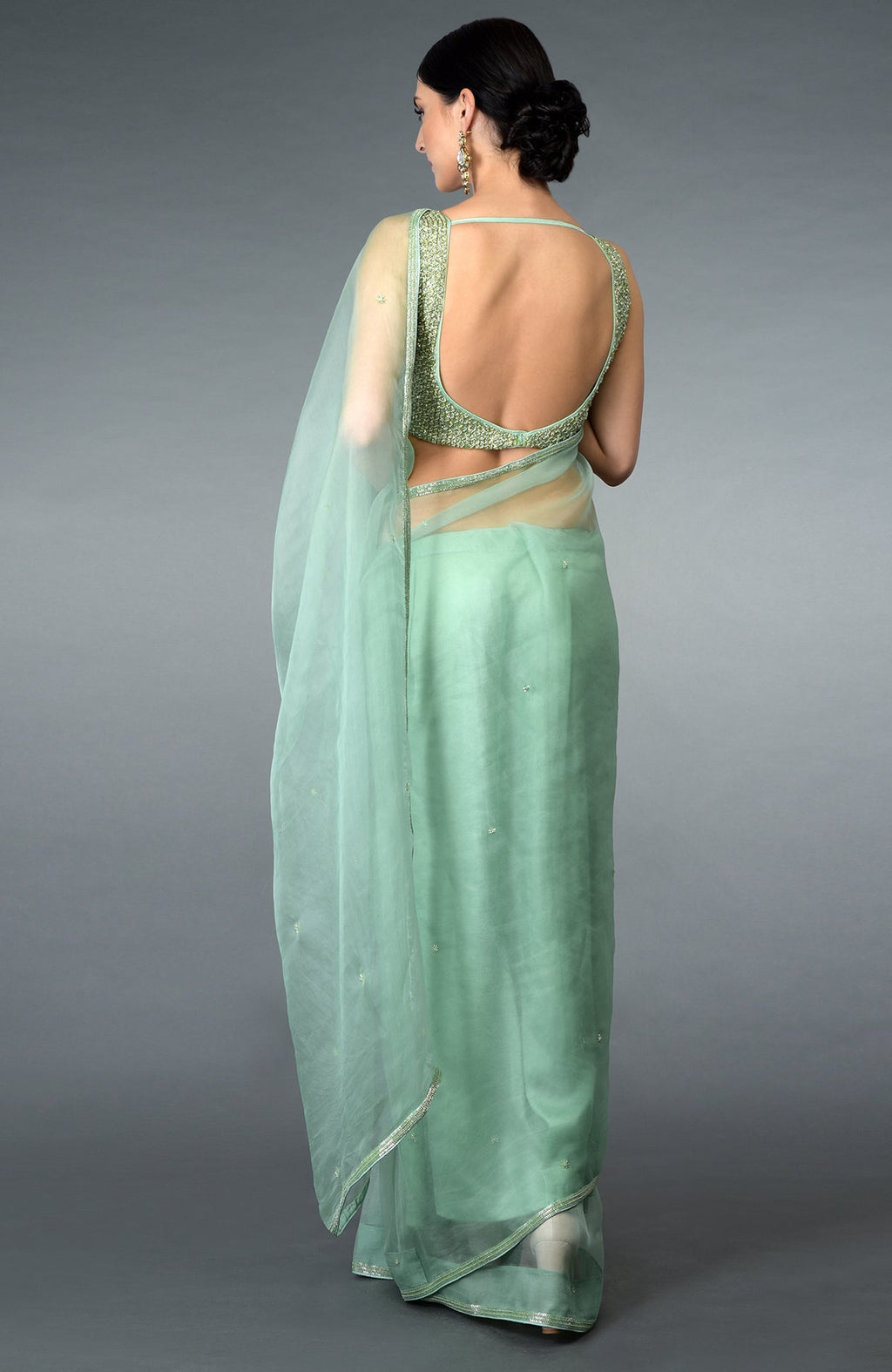 Mint green organza silk saree with a deep back blouse, adorned with beads and crystals.