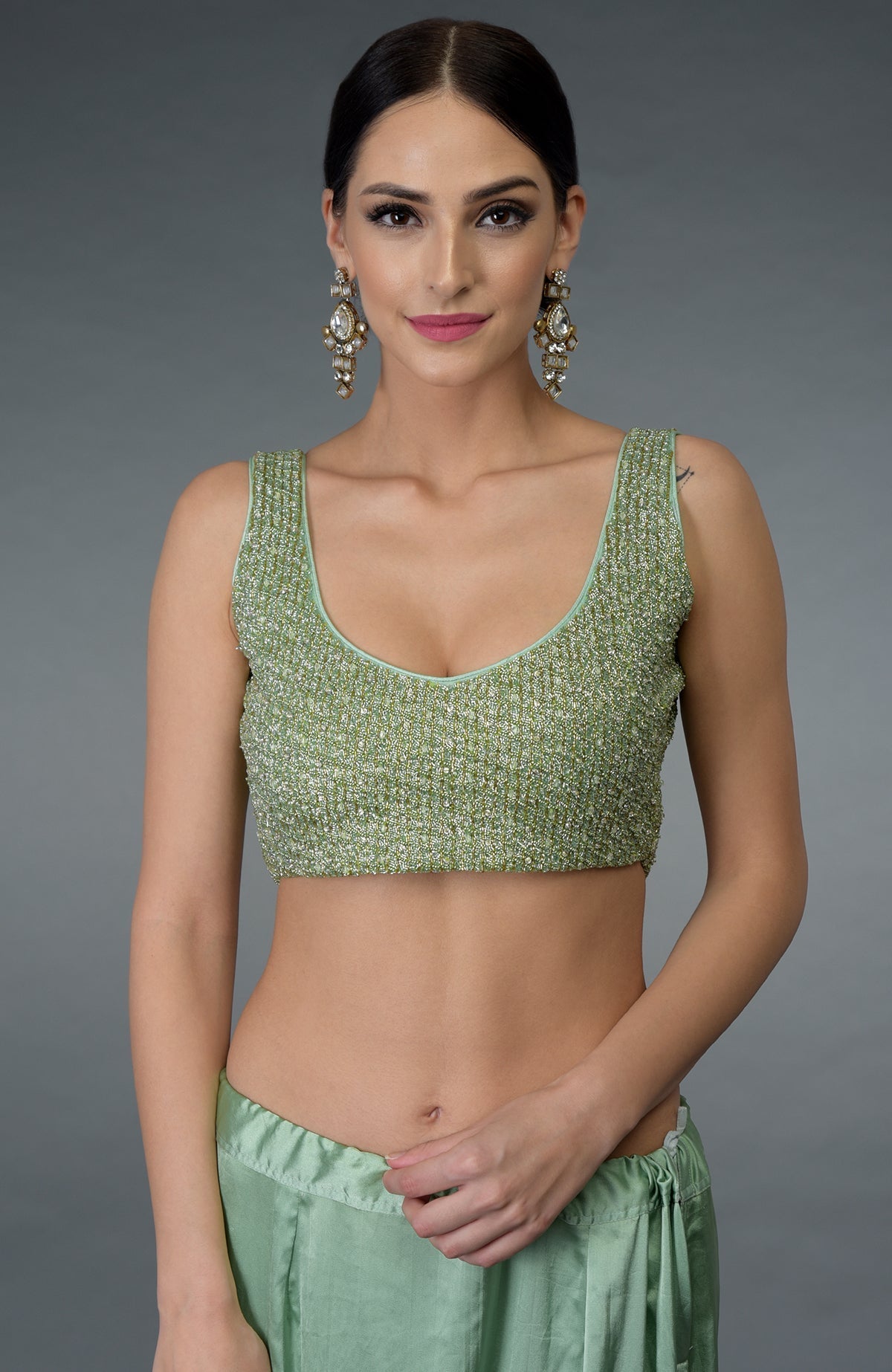 A woman models a mint green hand-embroidered blouse and matching saree.