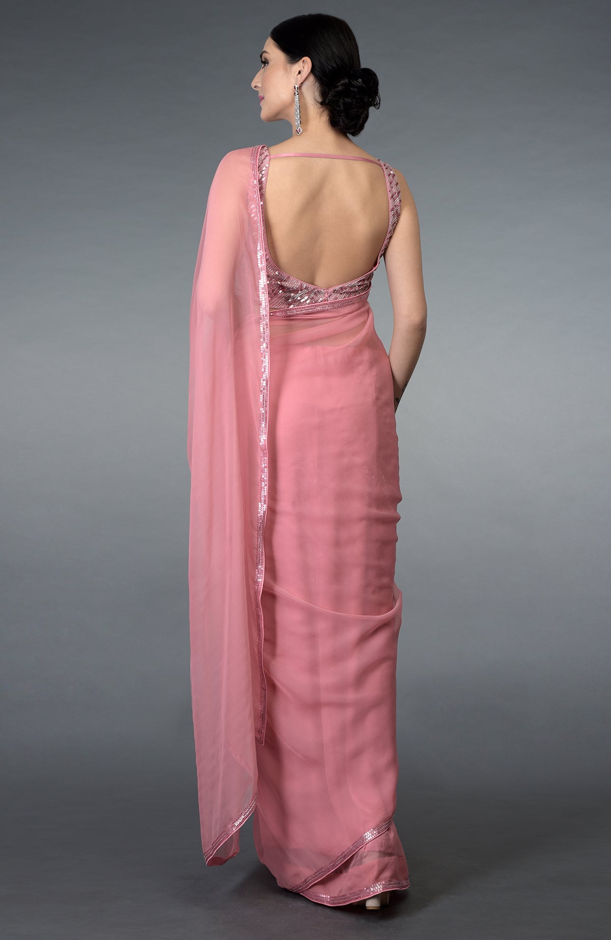 A woman models a pressed rose sequin and beads work saree with a backless blouse.