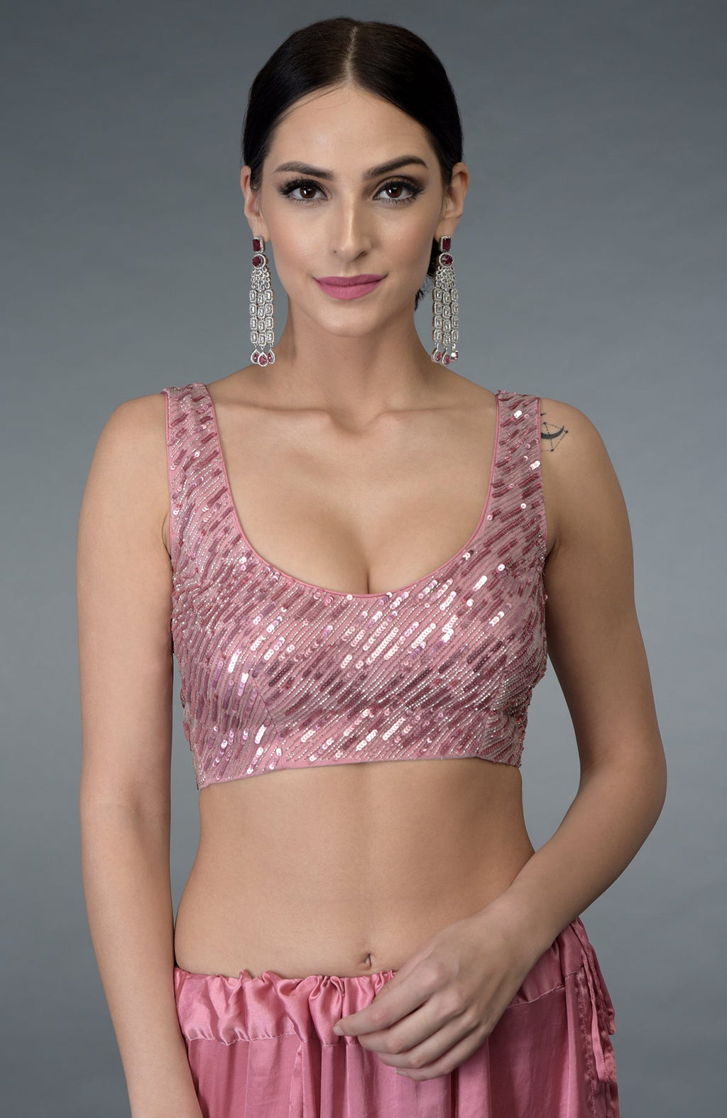 A woman models a pressed rose sequin and beads work saree with a matching blouse.