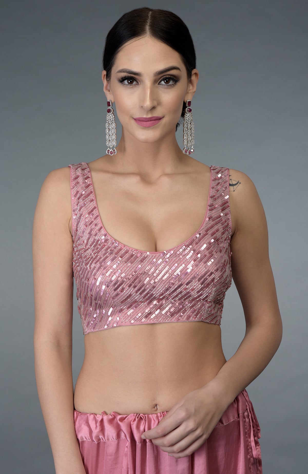 A woman models a pressed rose sequin and beads work saree with a matching blouse.