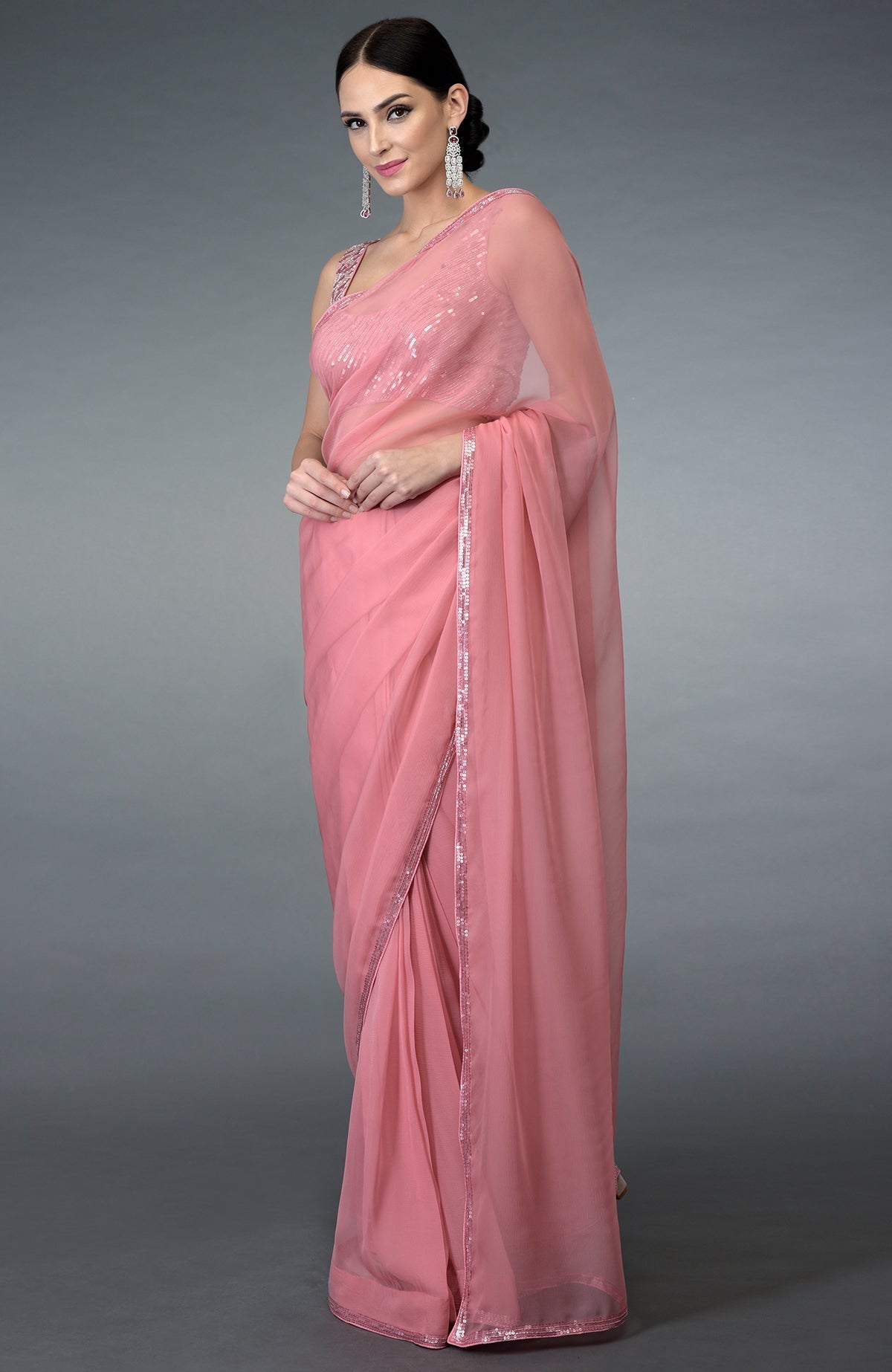 A woman models a pressed rose pure chiffon saree with sequin and bead work.