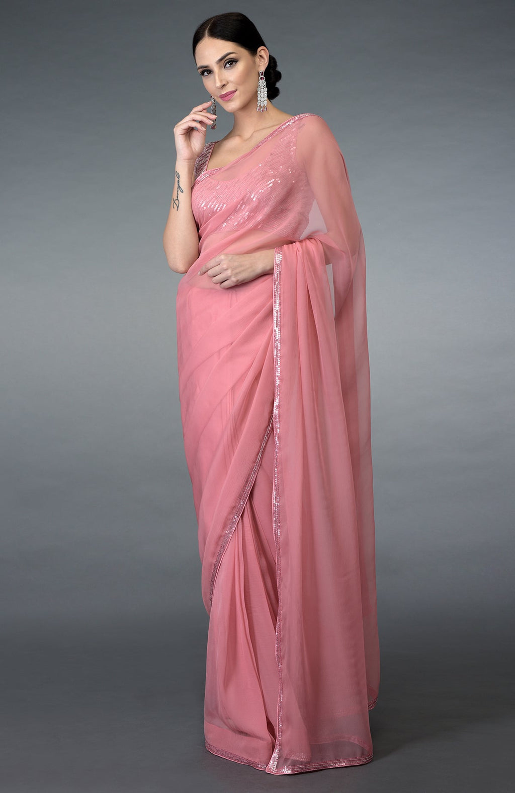 A woman models a pressed rose sequin and beads work saree with a matching blouse.
