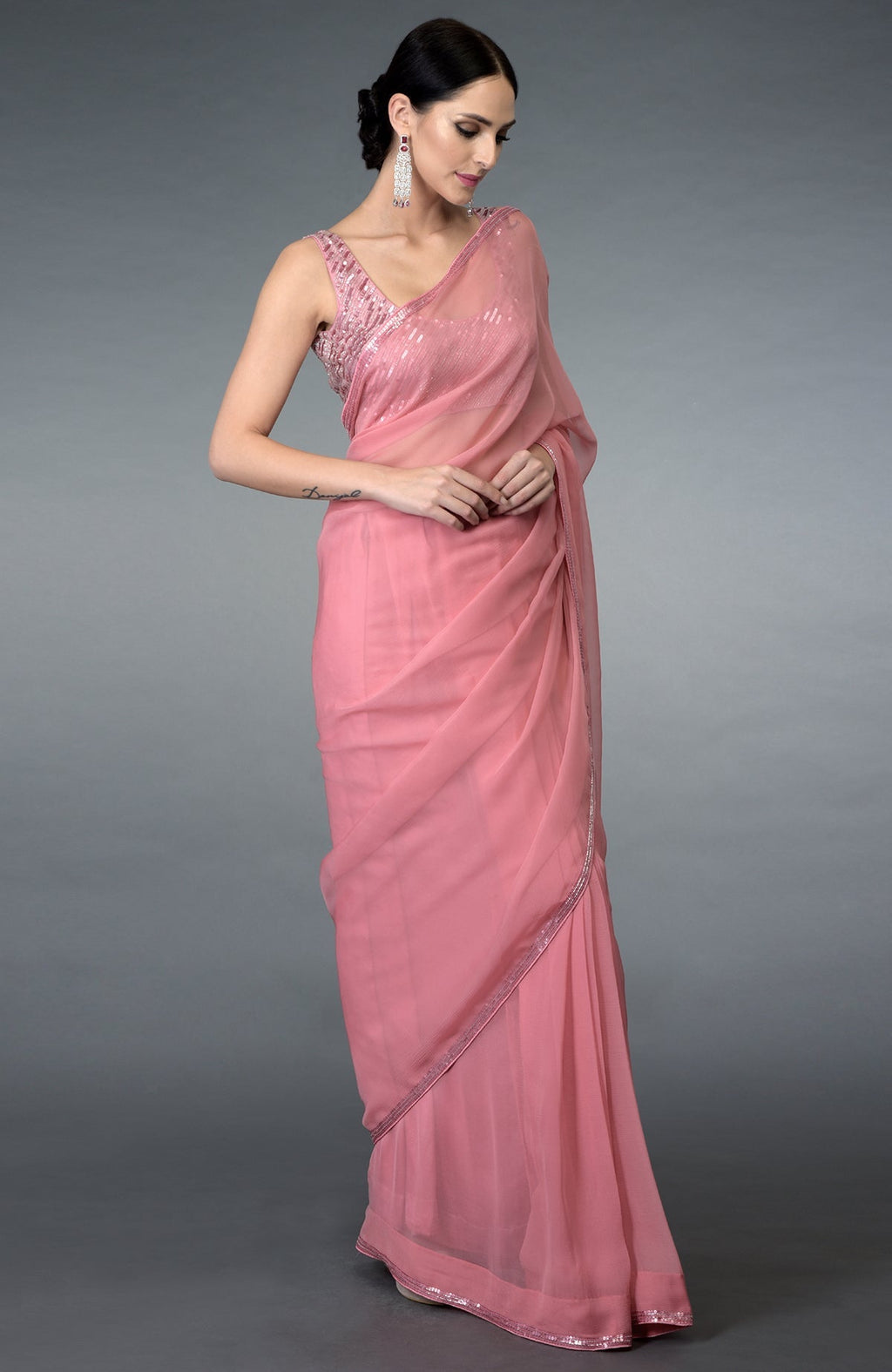 A woman models a pressed rose sequin and beads work saree with a matching blouse.