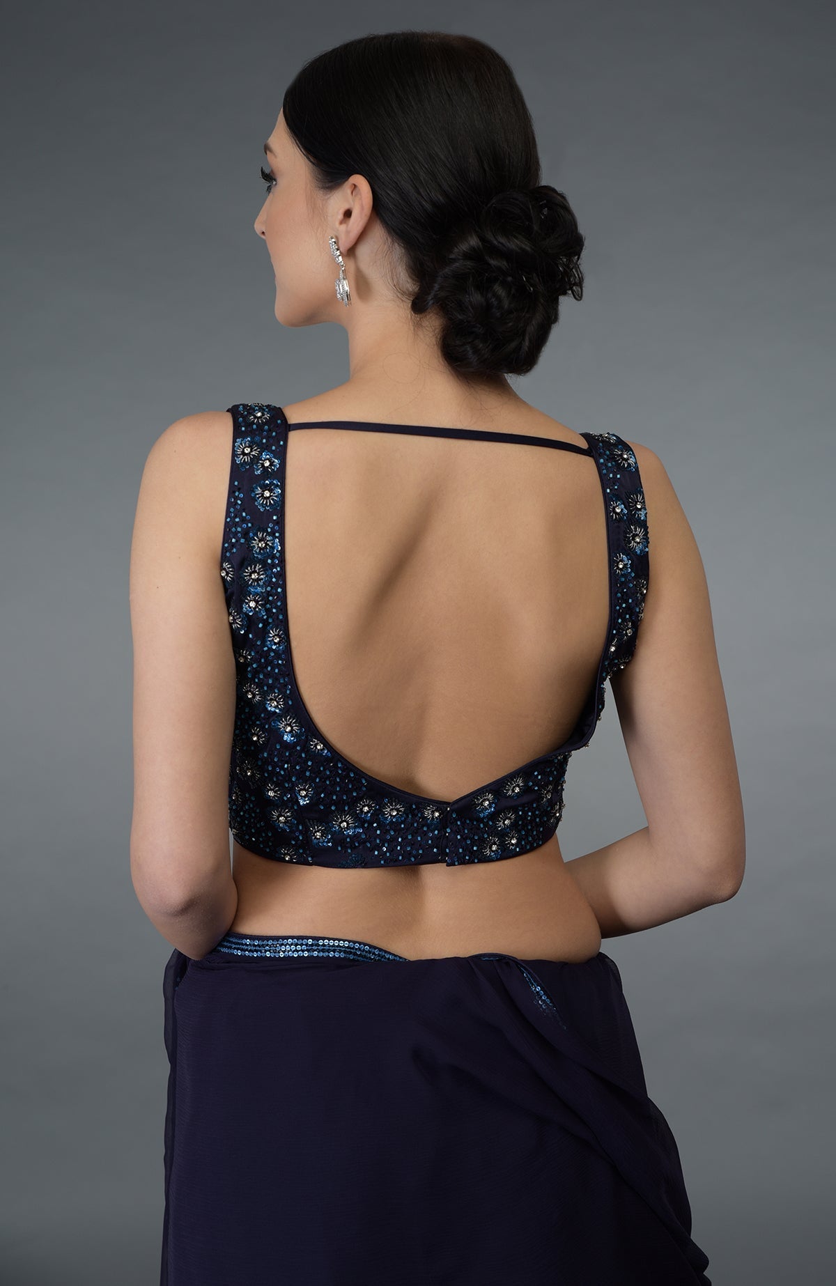 A woman from behind wearing an eclipse blue crystal sequin and beads work saree with blouse.