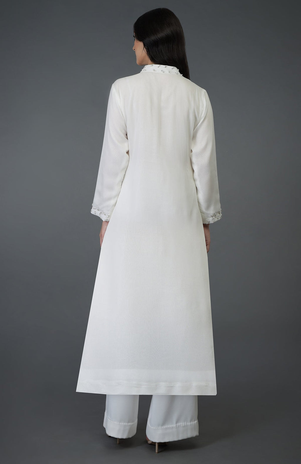 A woman from behind wears an off-white kurta set with crystal and pearl bead embroidery.