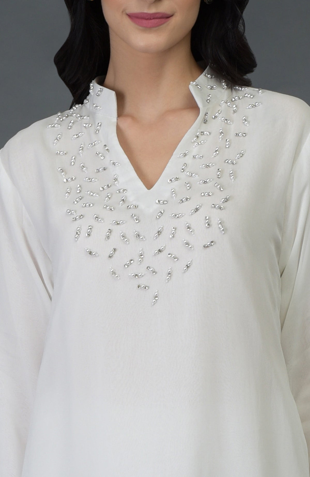 An off-white kurta with silver crystal and pearl bead embroidery on the front yoke.