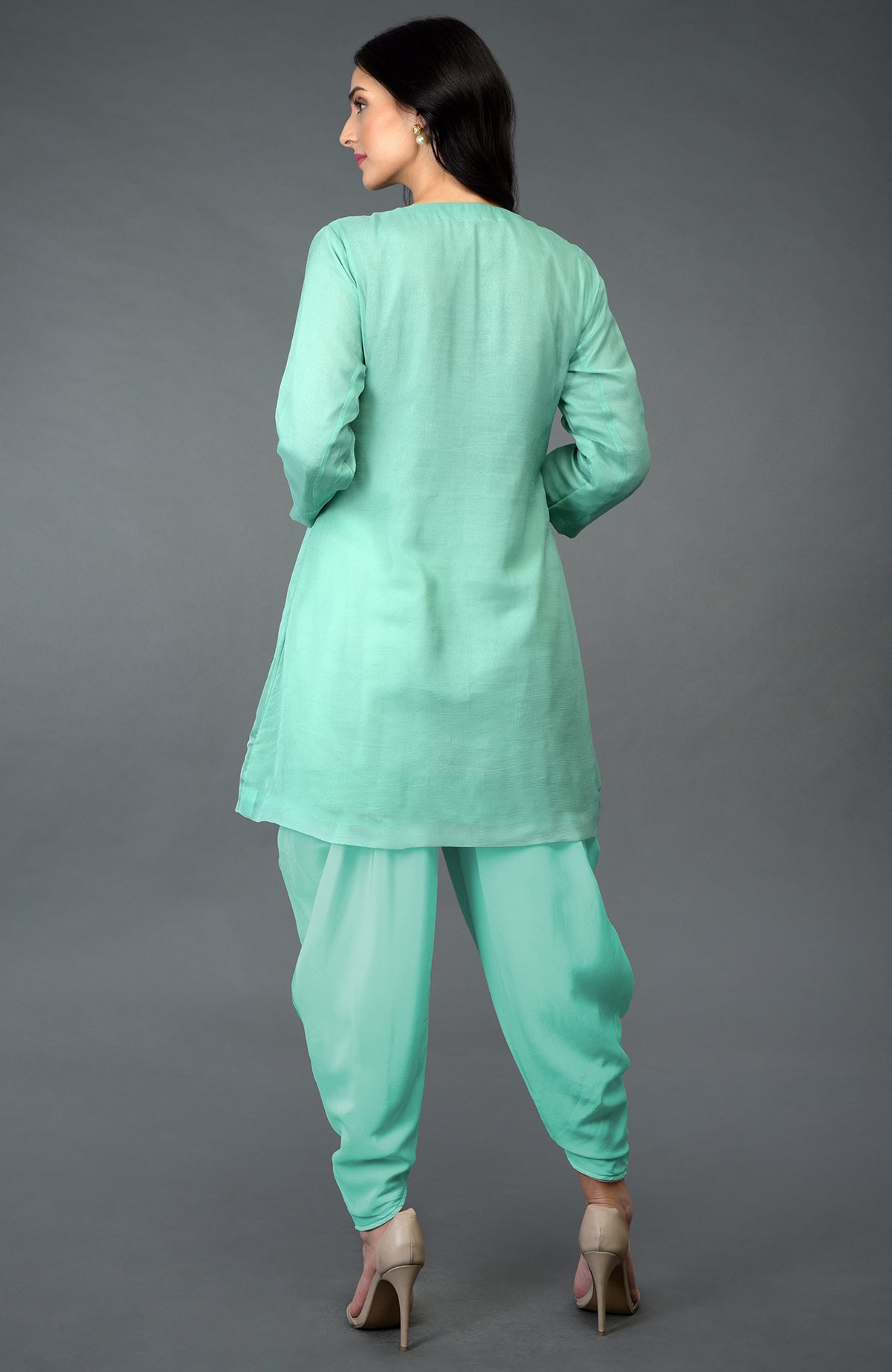 A woman models a mint green sequin and beads embroidered dhoti pants suit from the back.