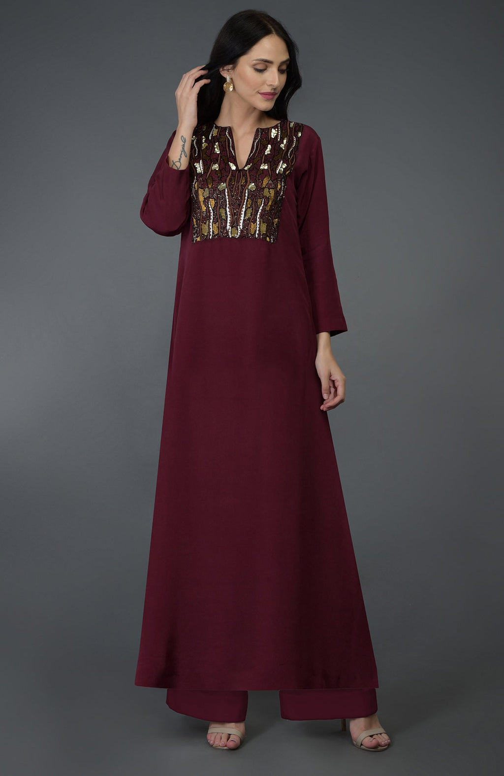A woman models a burgundy kurta set with intricate embroidery on the yoke.