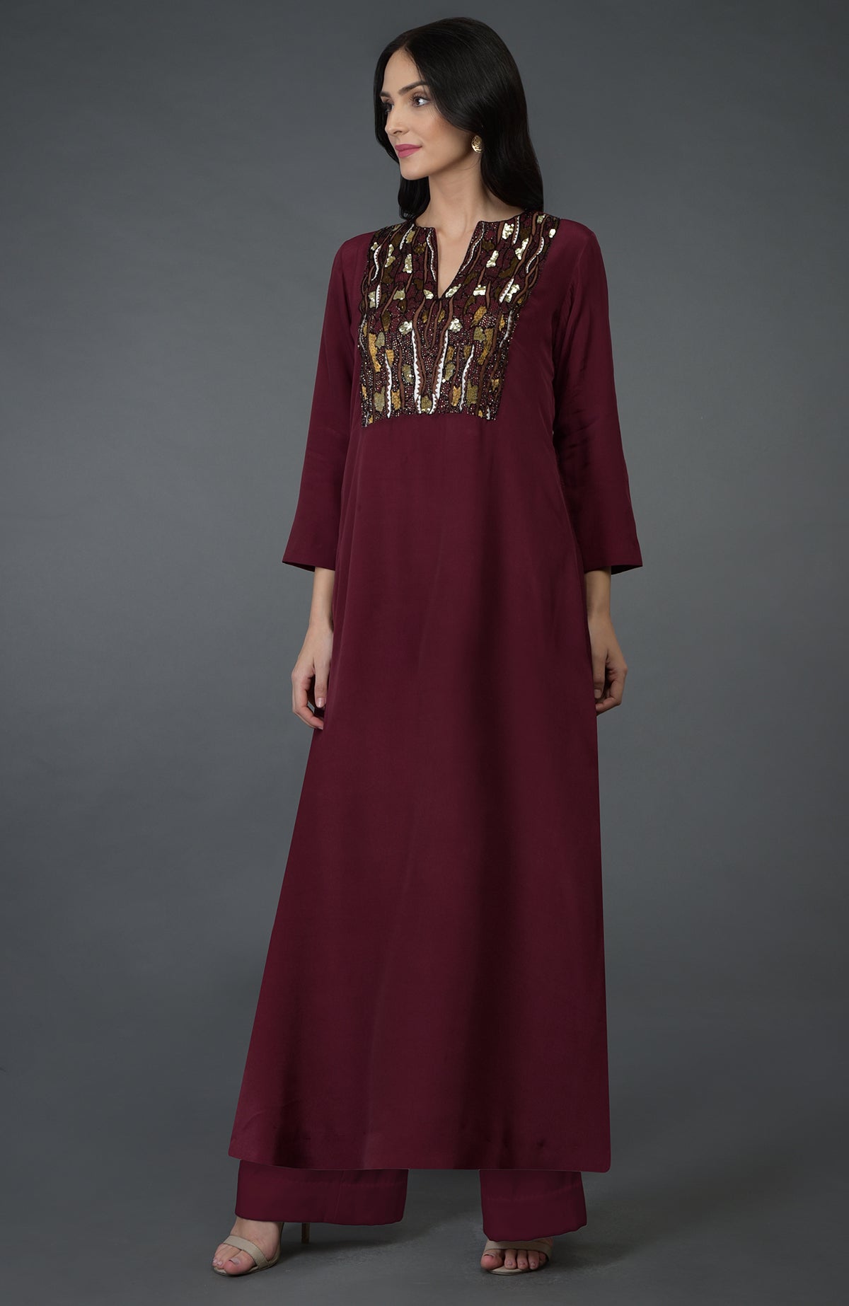 A woman models a burgundy kurta set with sequin and bead embroidery on the yoke.
