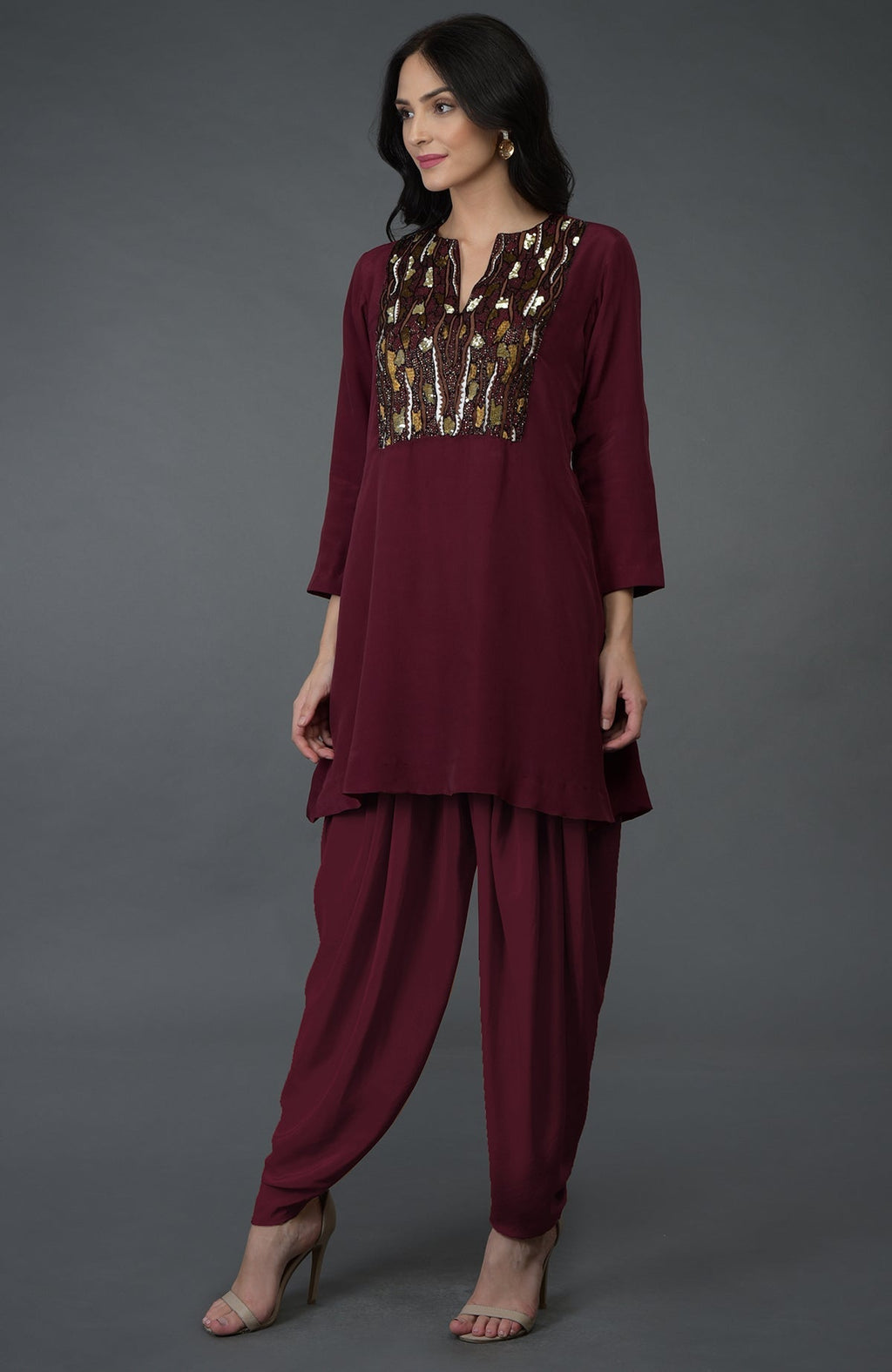 A woman models a burgundy dhoti pants suit with sequin and bead embroidery.