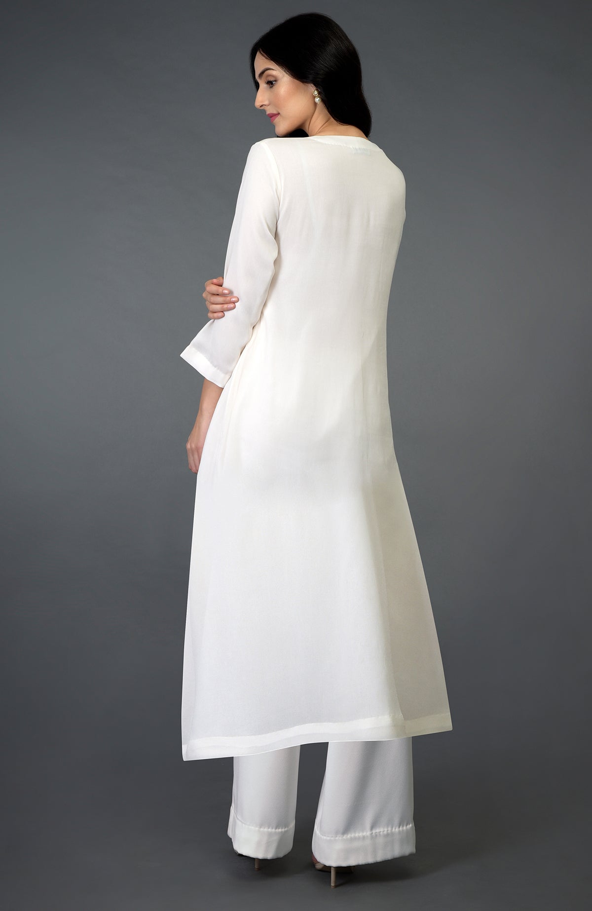A woman models an ivory kurta set with a long tunic and wide-leg pants.
