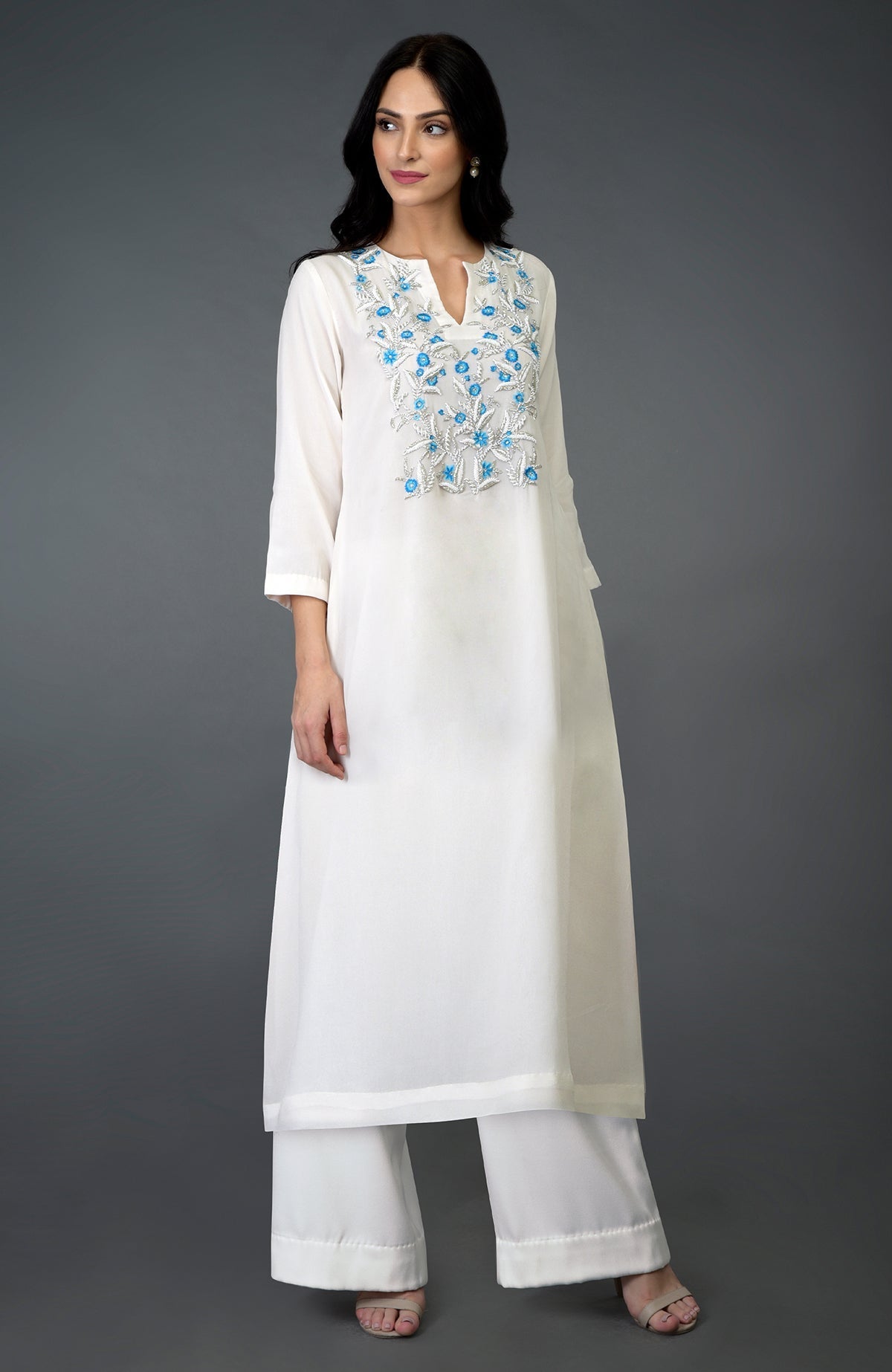 An ivory kurta set with turquoise resham, beads, and crystal embroidery on the yoke.