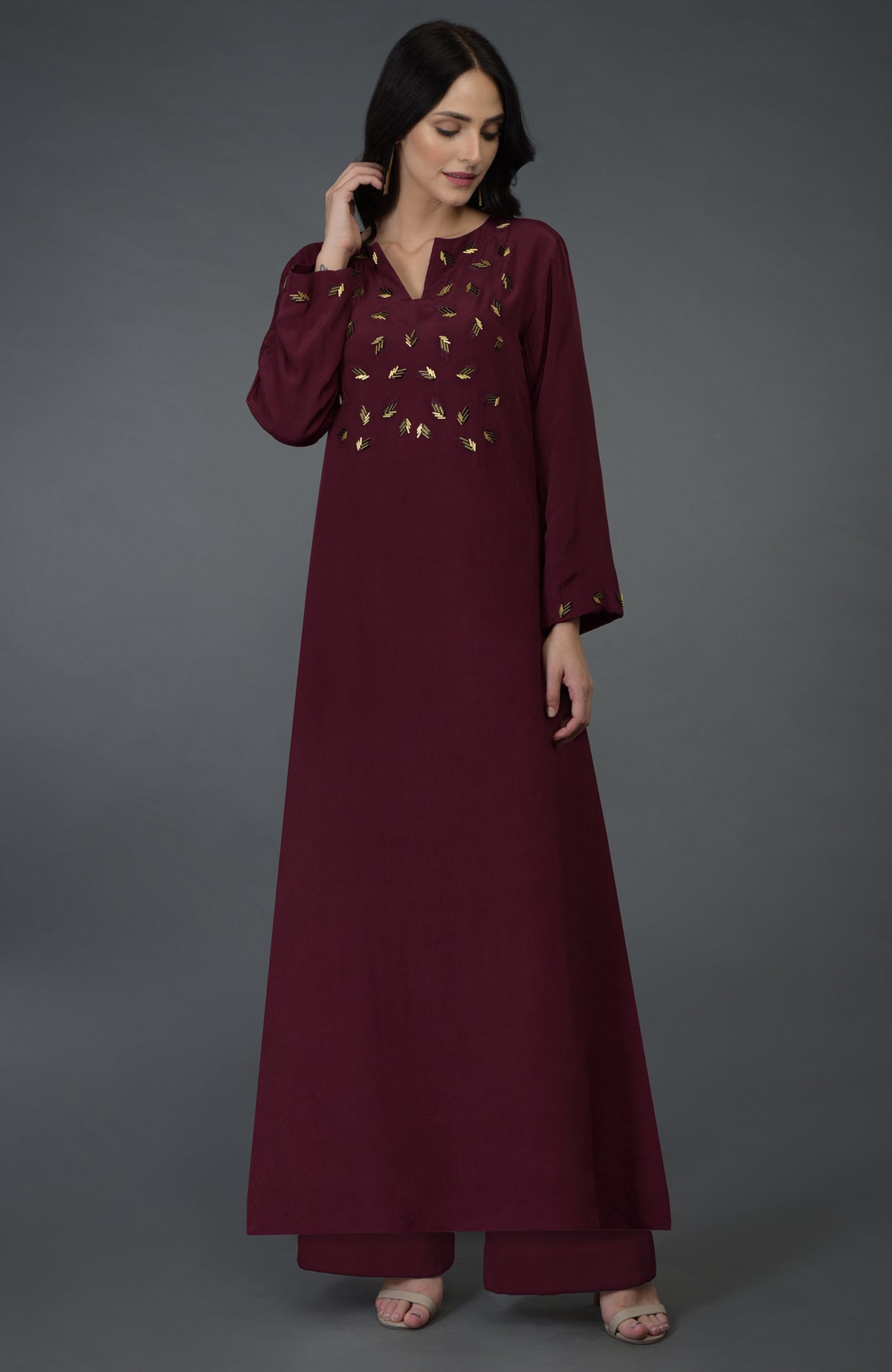 A woman models a burgundy kurta set with gold bugle bead embroidery.