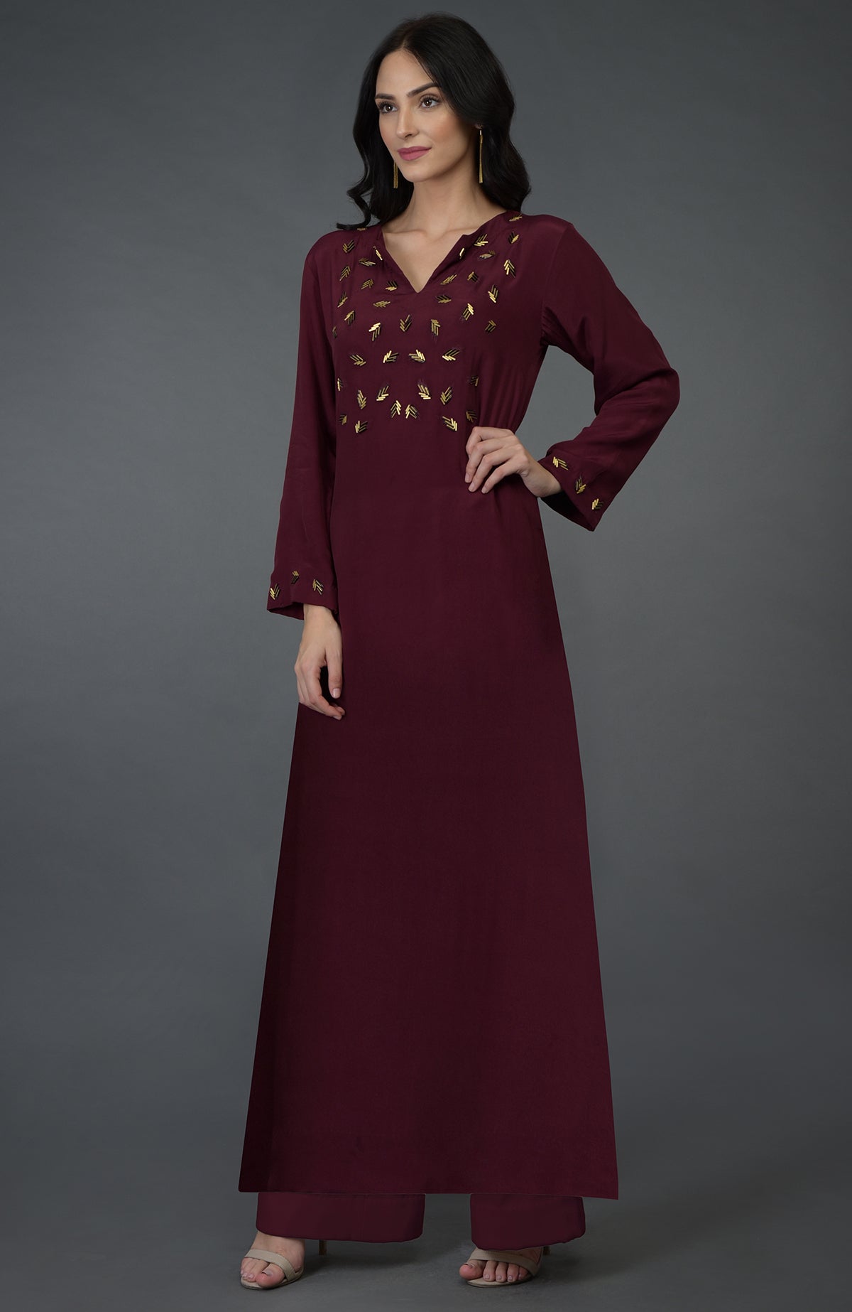 A woman models a burgundy kurta set with gold bugle bead embroidery.