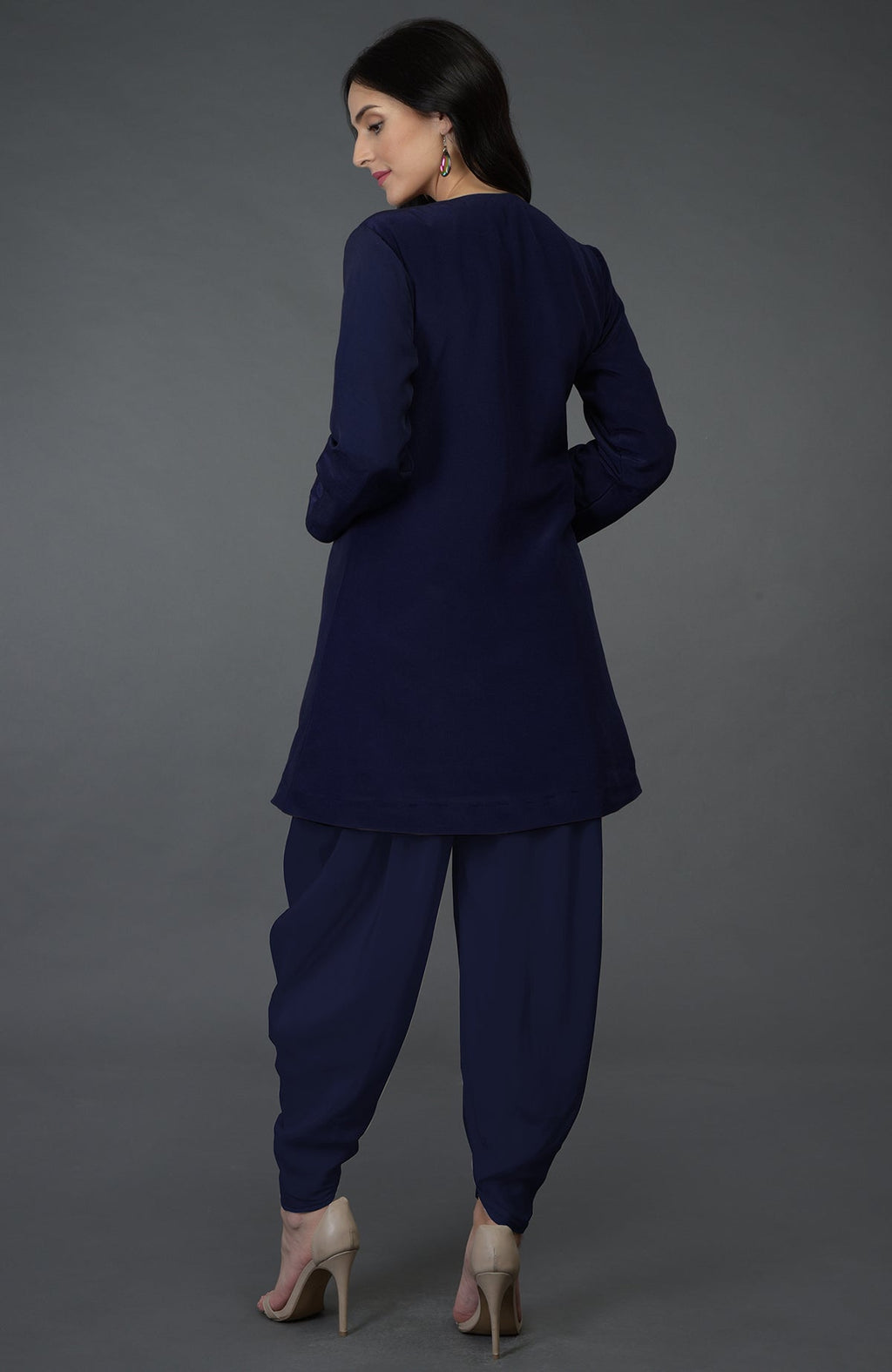 A woman from behind wears an eclipse blue top with dhoti pants and nude heels.