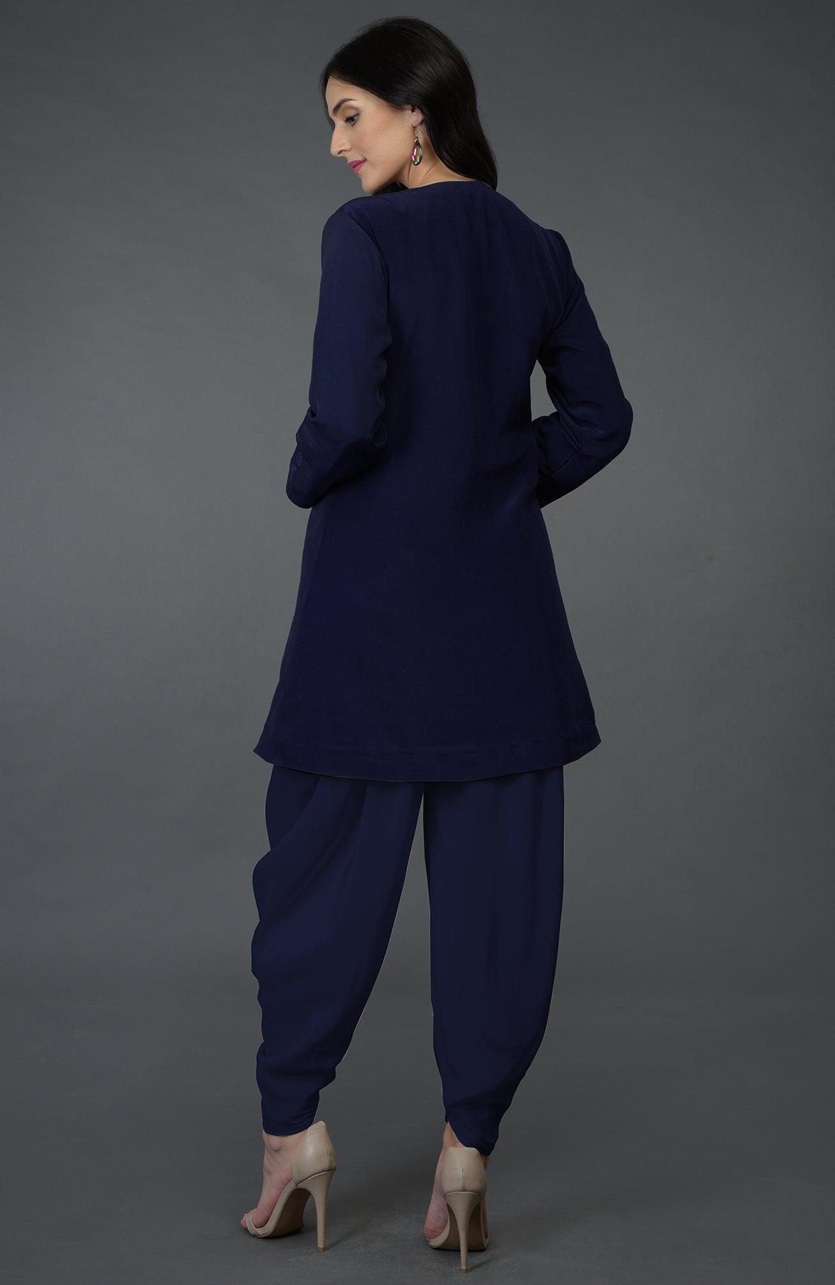 A woman from behind wears an eclipse blue top with dhoti pants and nude heels.