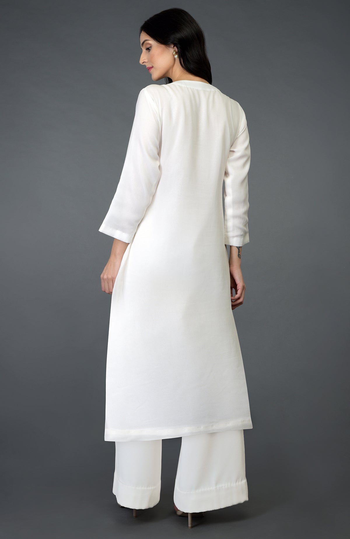 A woman models an ivory kurta set with floral embroidery on the yoke.