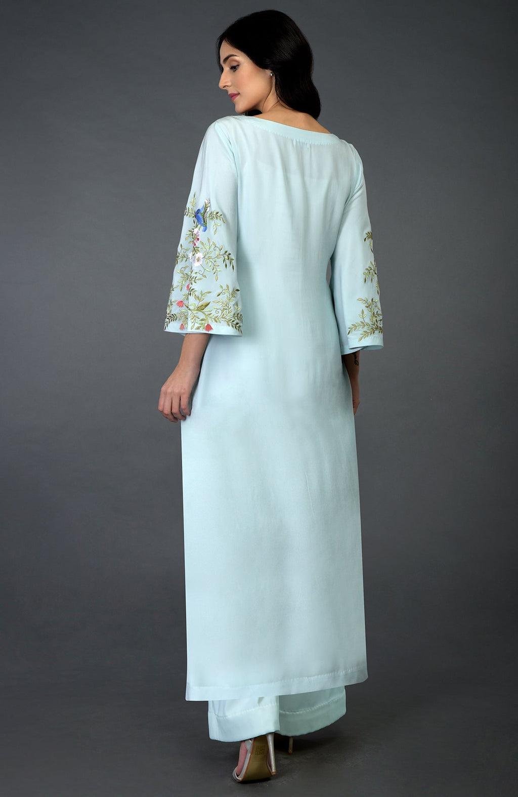 A woman models a serenity blue kurta set with bird and floral embroidery on the sleeves.