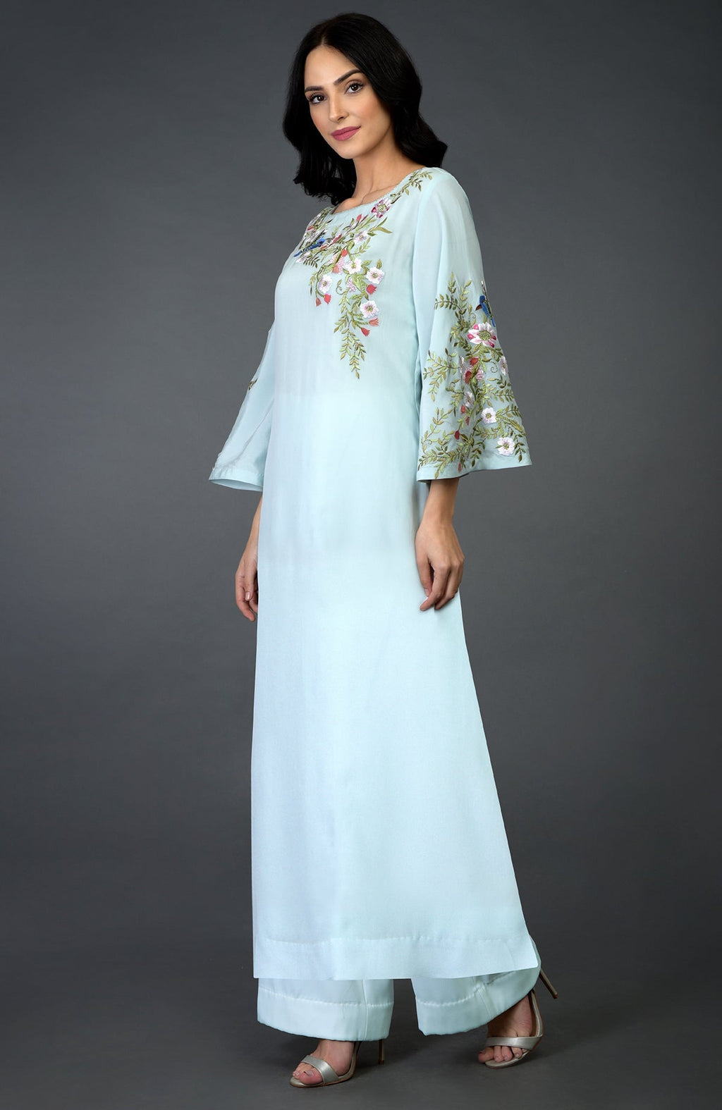 A woman models a serenity blue kurta set with floral and bird embroidery.