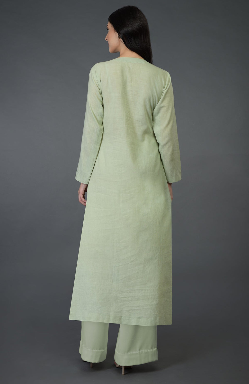 A woman from behind wears a pista green kurta set with long sleeves and wide-leg pants.