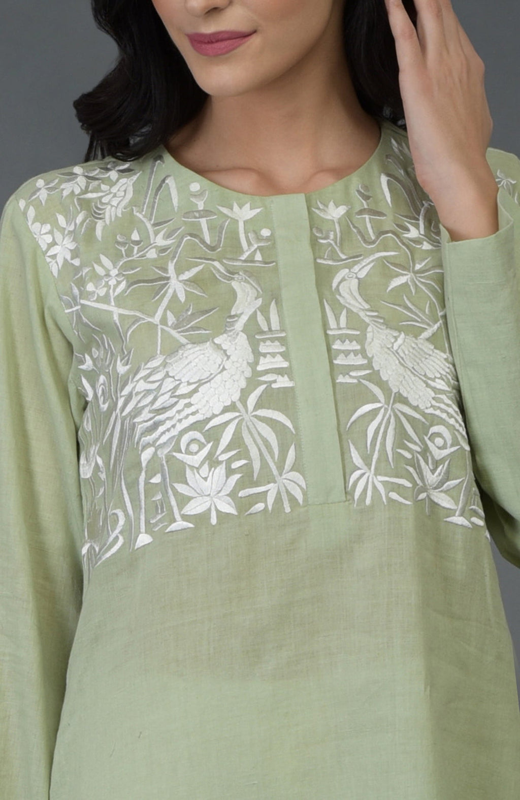 Pista green kurta with white birds and floral embroidery on the front yoke.
