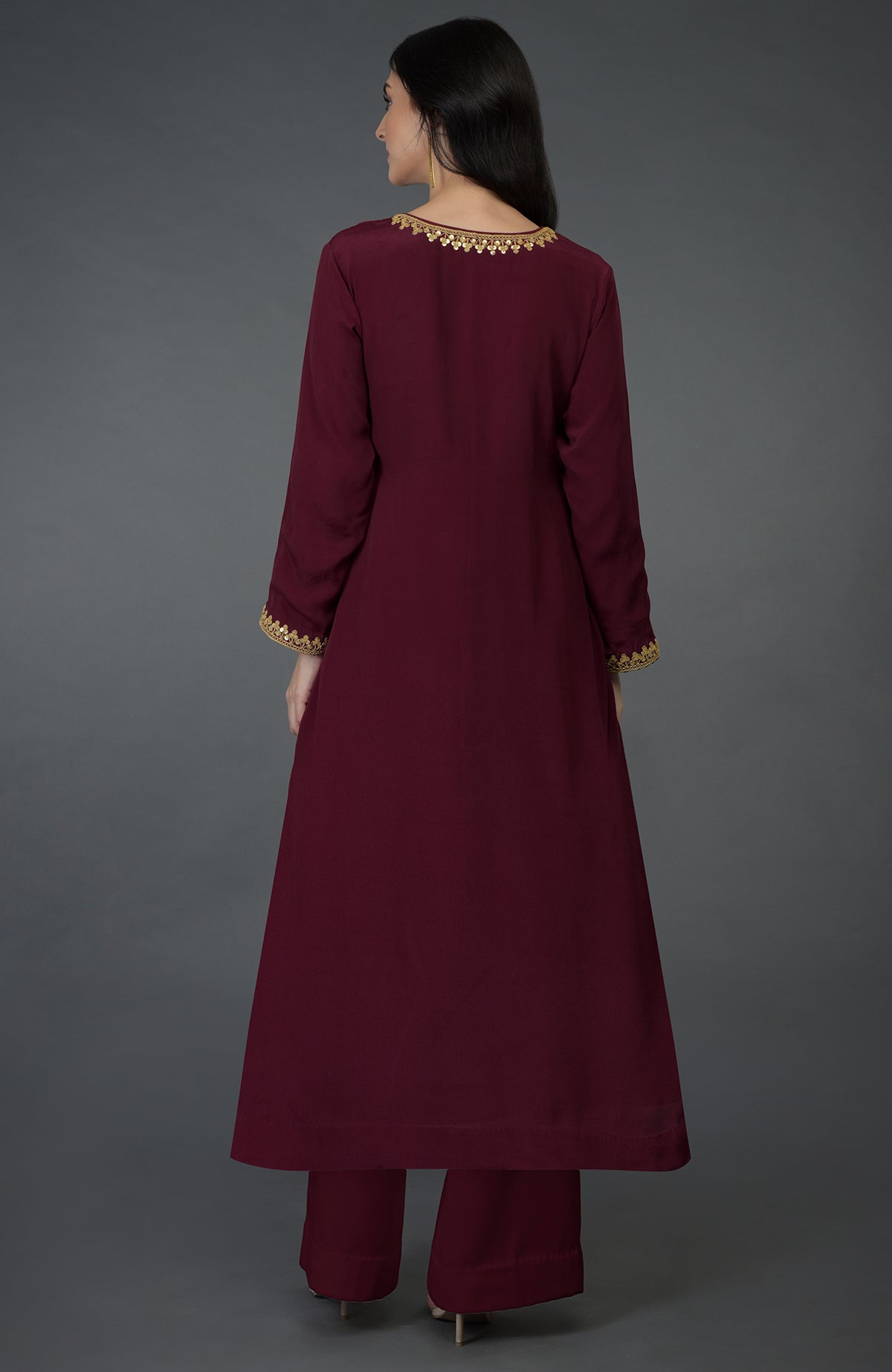 A woman models a maroon kurta set with gold marori and sequin embroidery.