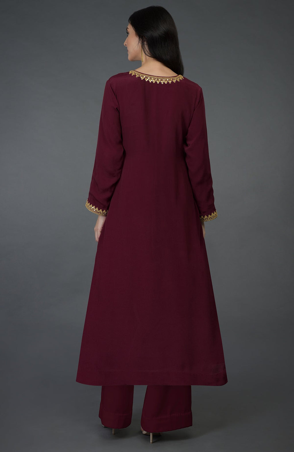 A woman models a burgundy kurta set with gold embroidery.