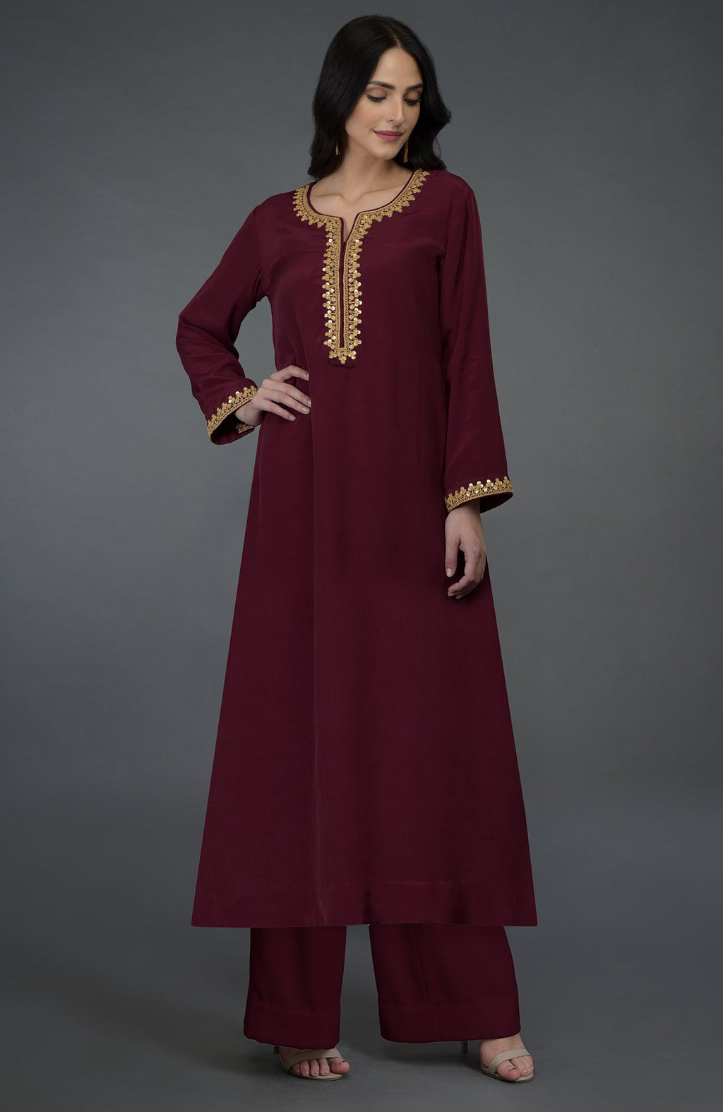 A woman models a maroon kurta set with gold marori and sequin embroidery.