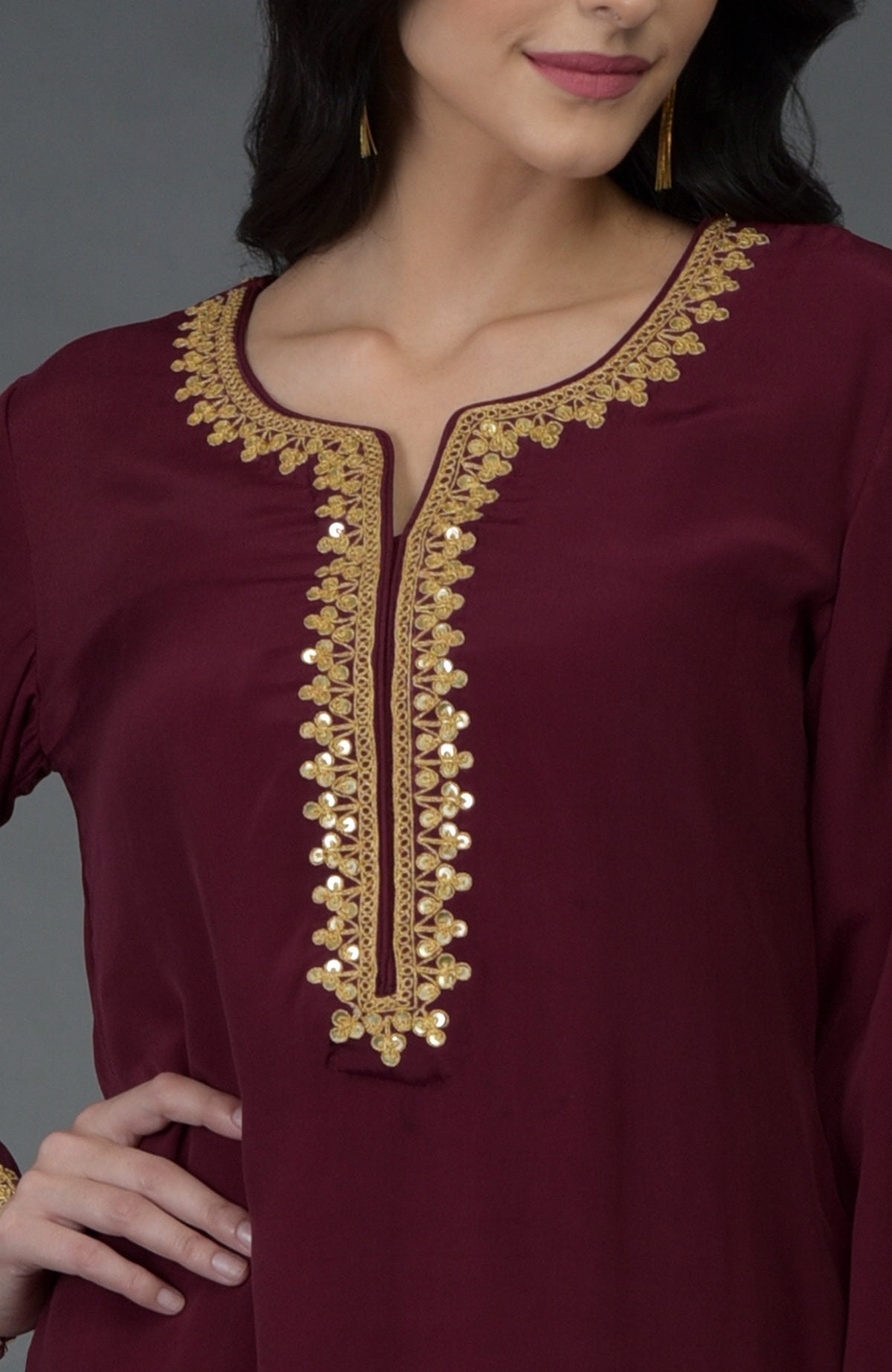 A woman models a maroon kurta with gold marori and sequin embroidery.