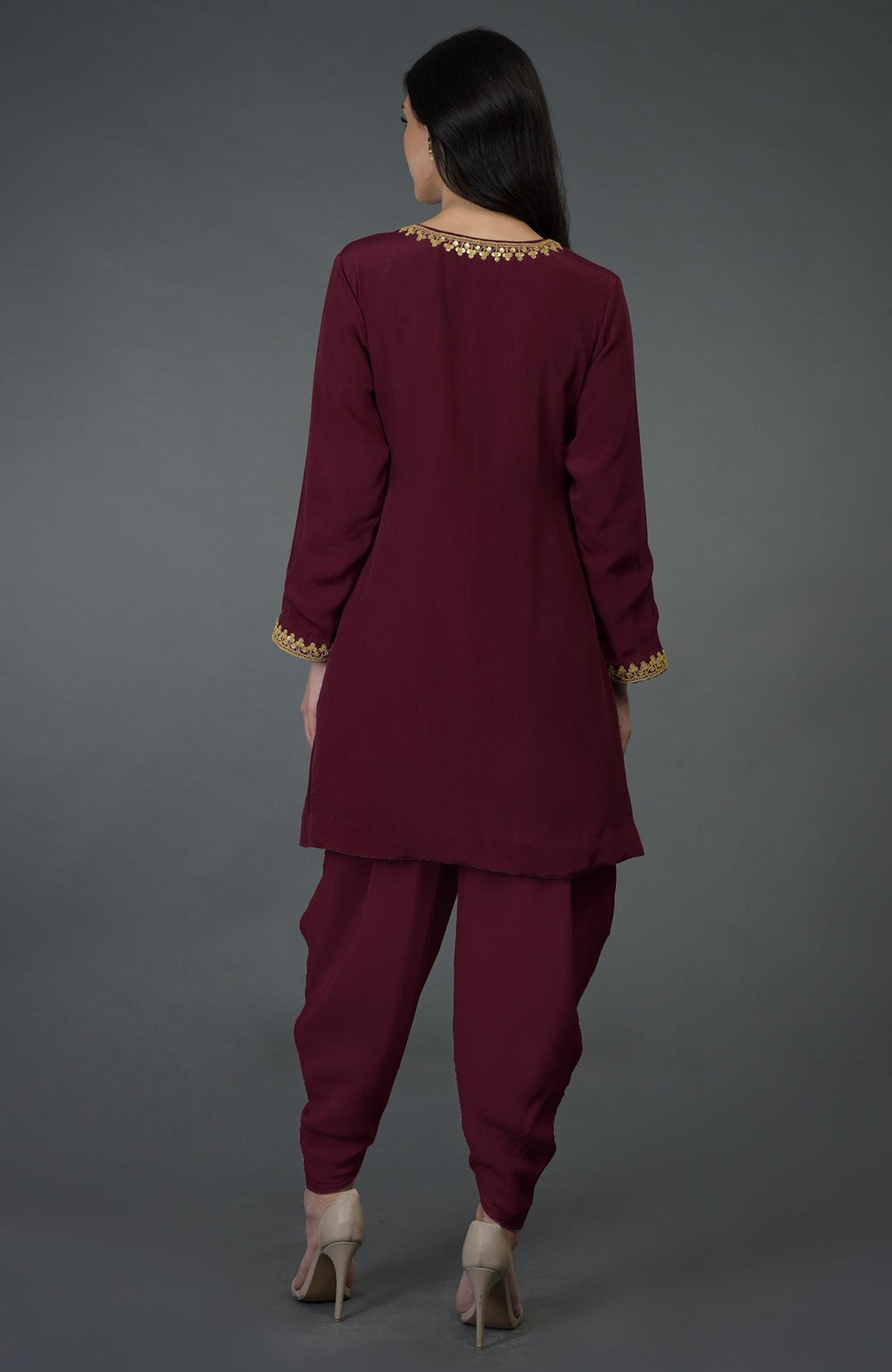 Rear view of a woman wearing a burgundy dhoti pants suit with gold embroidery.