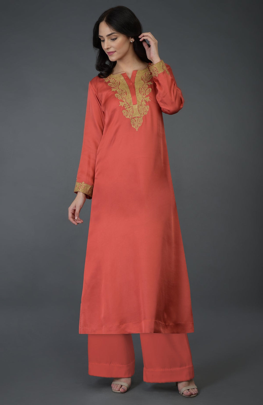 A woman models a living coral Kashmiri Tilla embroidered kurta set.