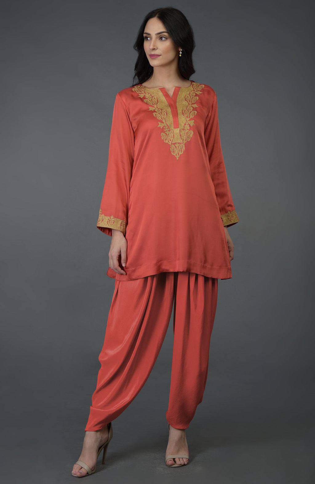 A woman models a living coral Kashmiri tilla embroidered dhoti pants suit.