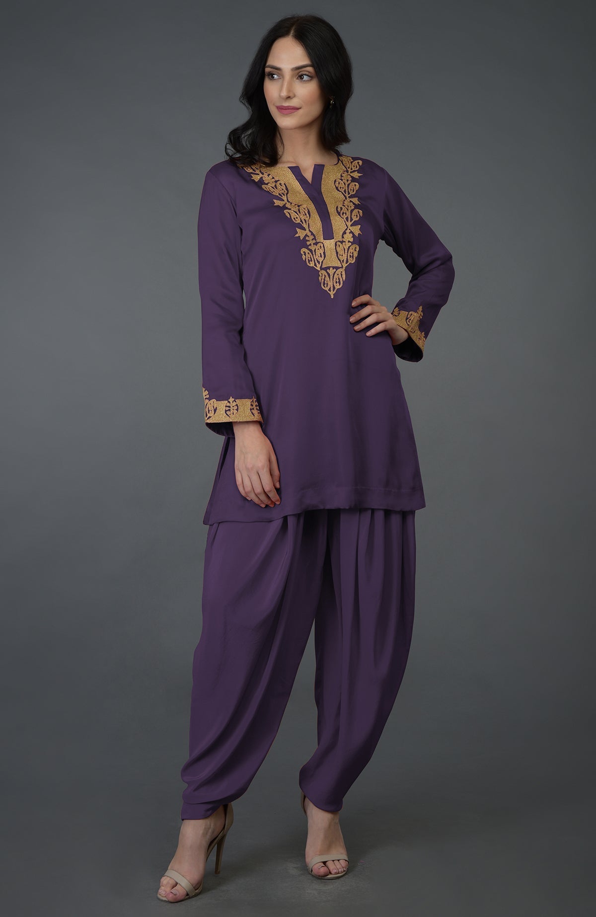 A woman models a purple dhoti pants suit with gold Kashmiri tilla embroidery.