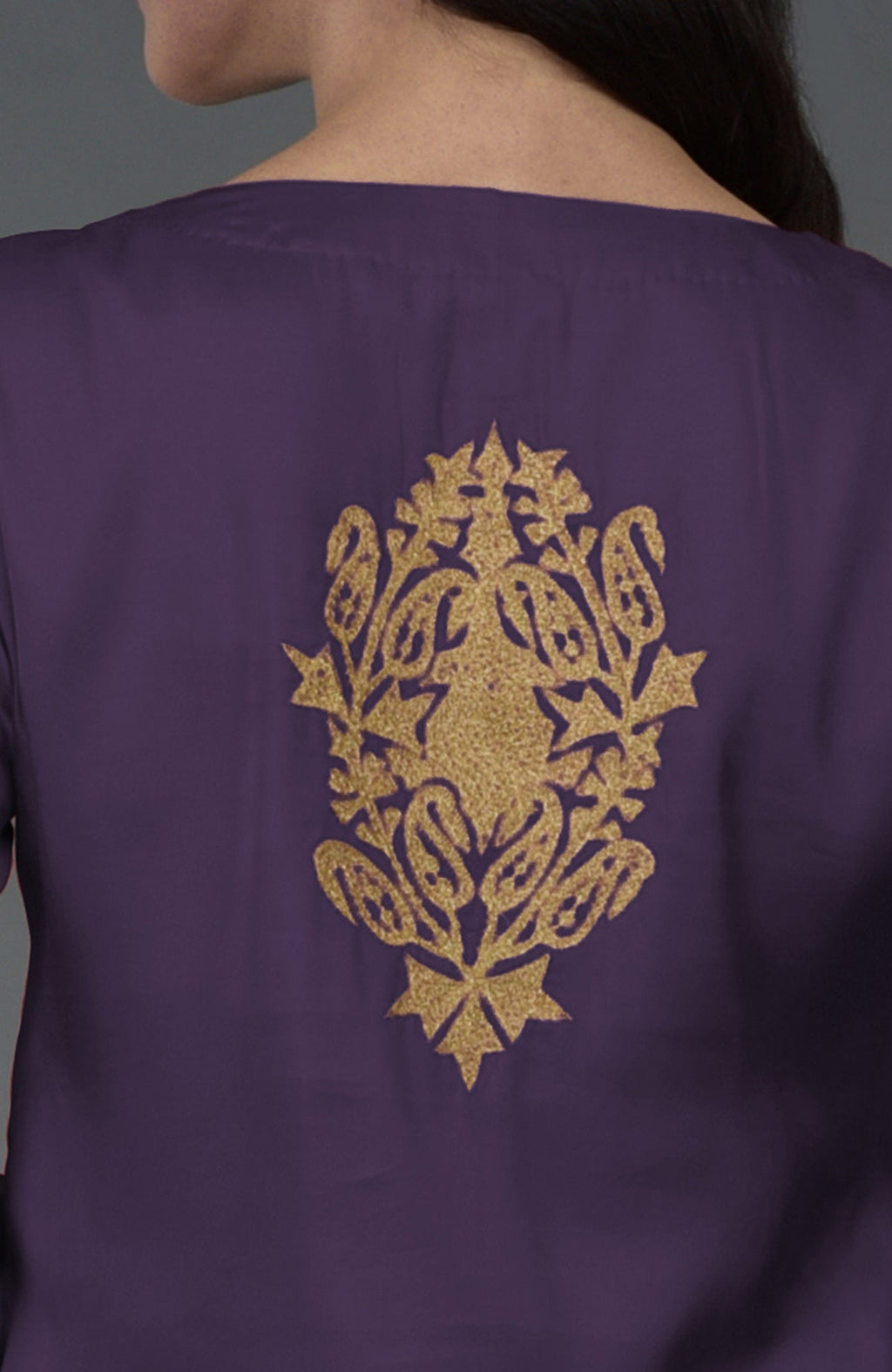 A woman models a mulled grape tunic with gold Kashmiri tilla embroidery on the back.