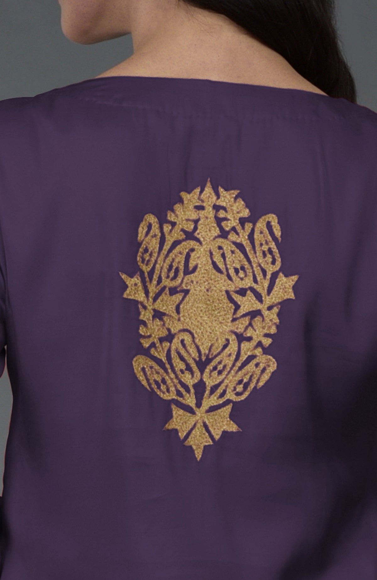 A woman models a mulled grape tunic with gold Kashmiri tilla embroidery on the back.