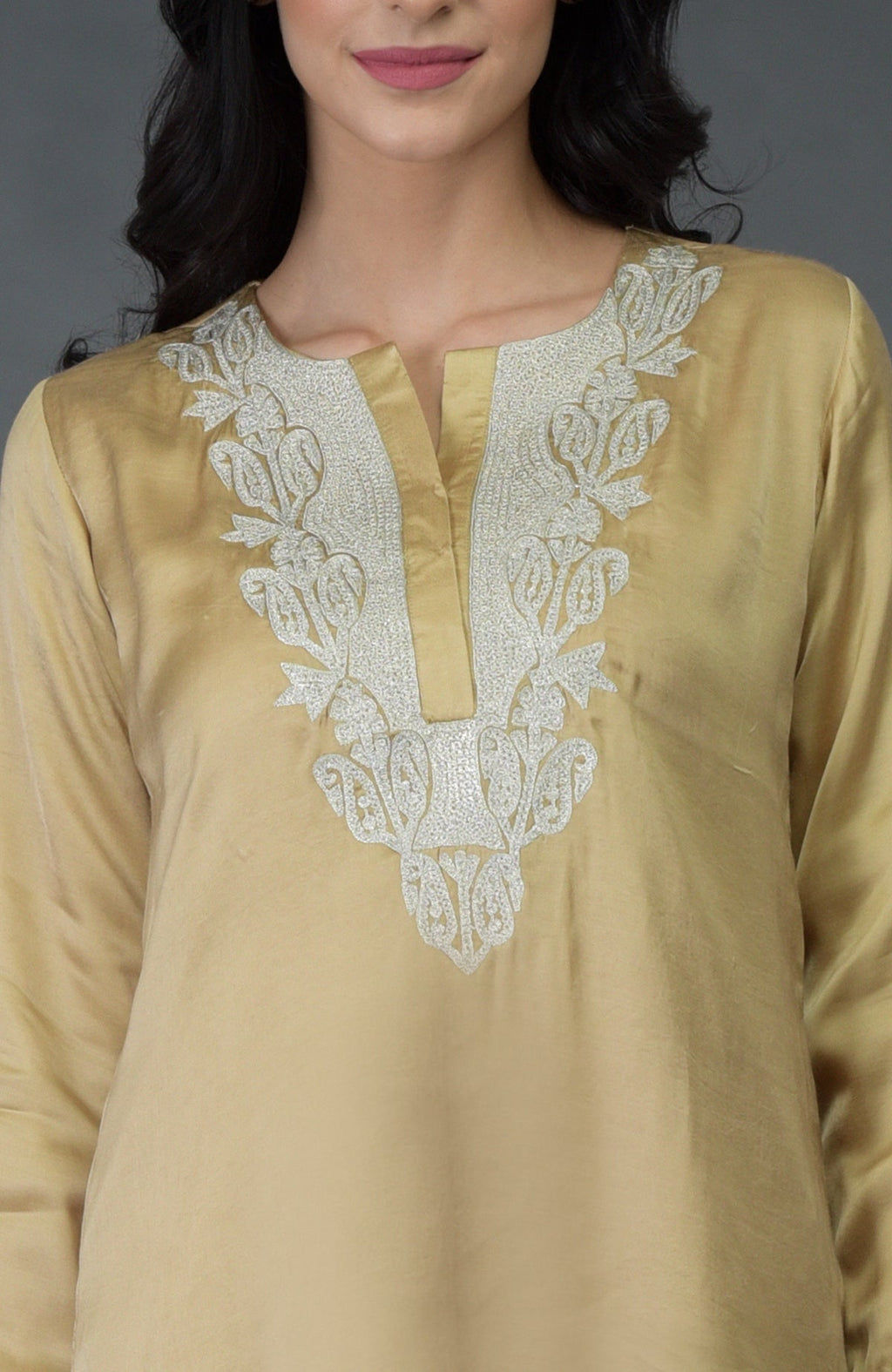 A woman models a beige gold Kashmiri tilla embroidered kurta set.