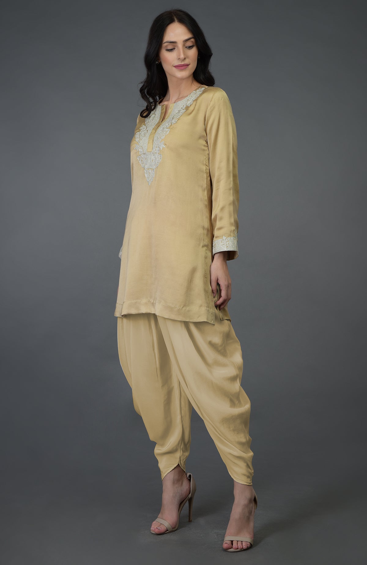A woman models a beige gold Kashmiri Tilla embroidered dhoti pants suit.