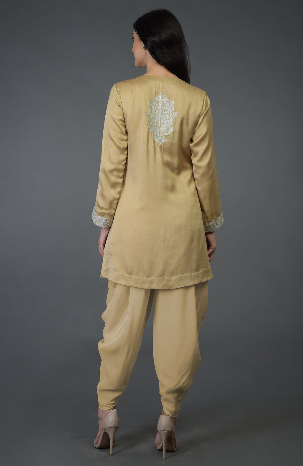 A woman from behind wears a beige gold Kashmiri tilla embroidered dhoti pants suit.