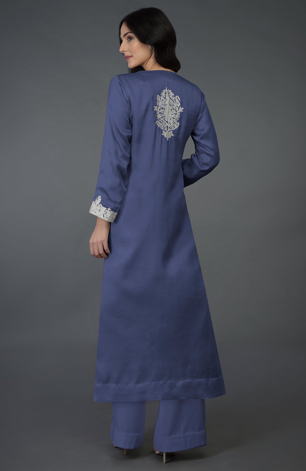 A woman models an iris blue Kashmiri tilla embroidered kurta set with silver embroidery.