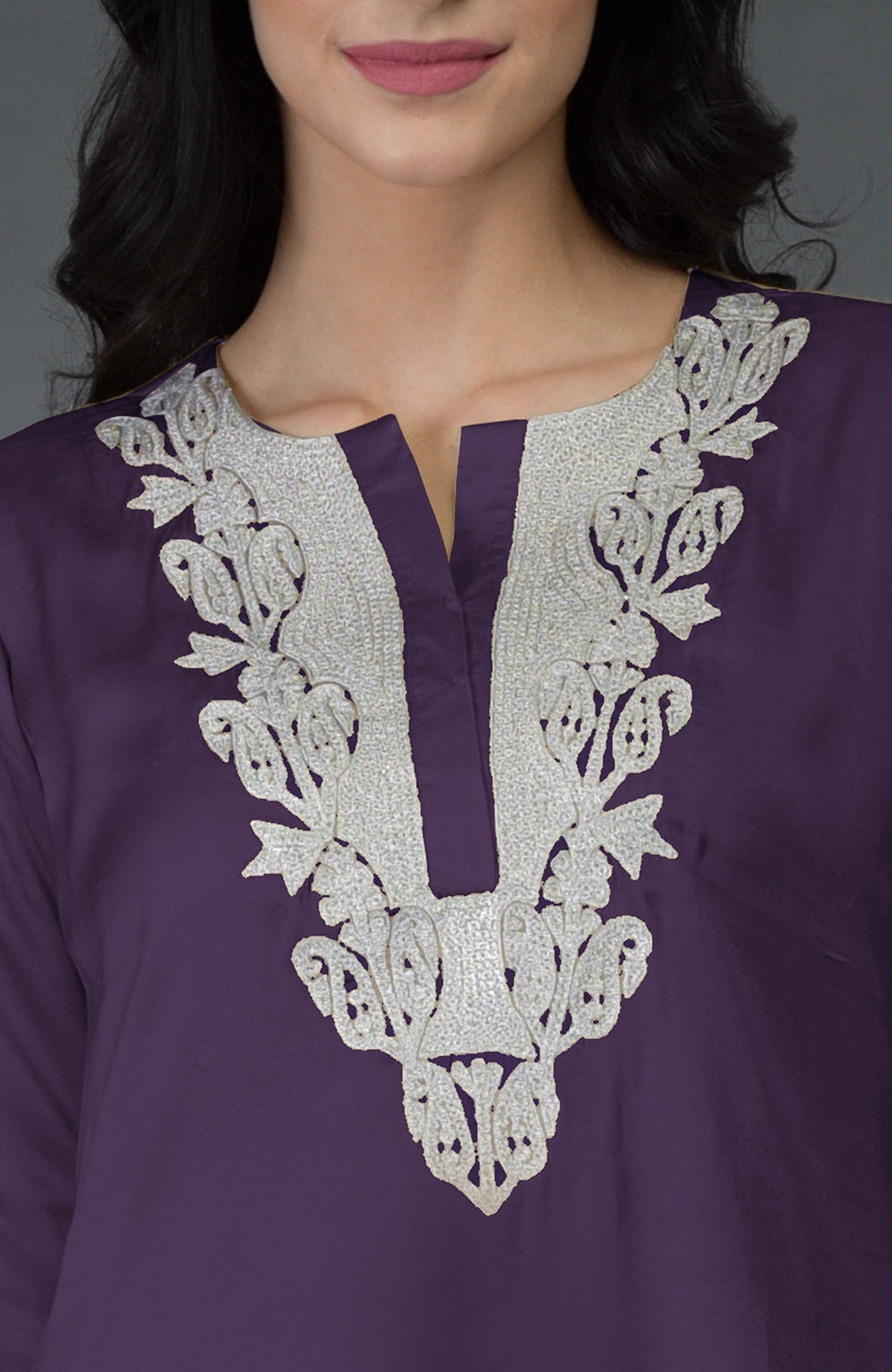 A woman wears a mulled grape kurta with silver Kashmiri tilla embroidery around the V-neck.