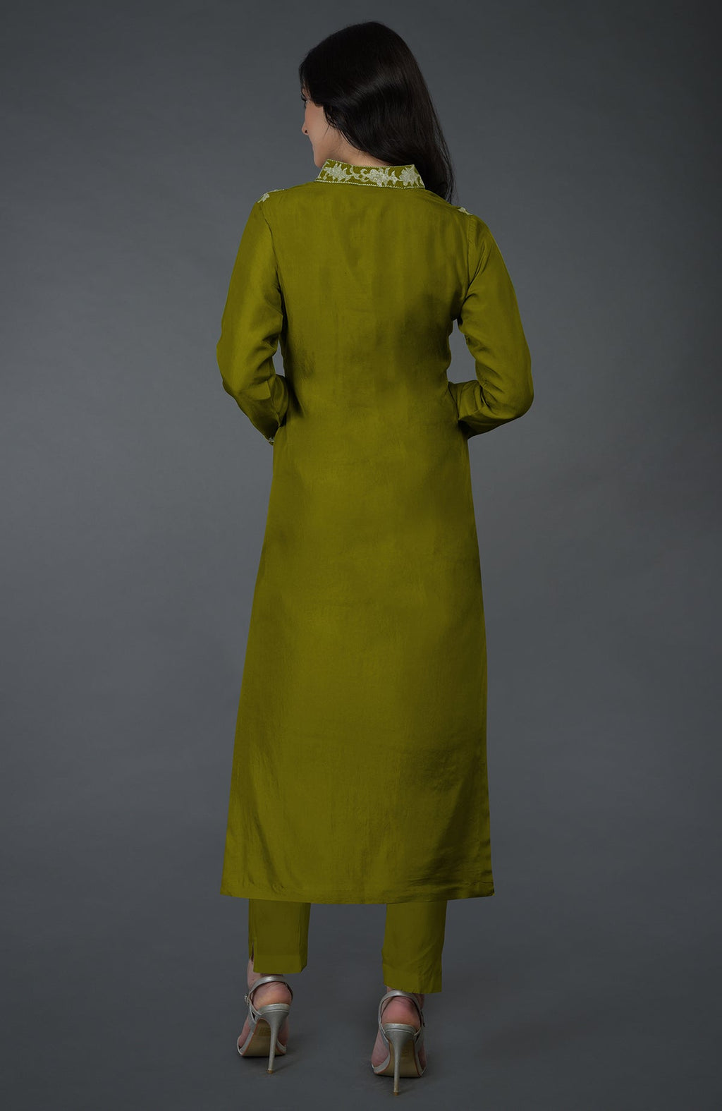 A woman from behind wears an olive Kashmiri Tilla embroidered kurta set with silver heels.