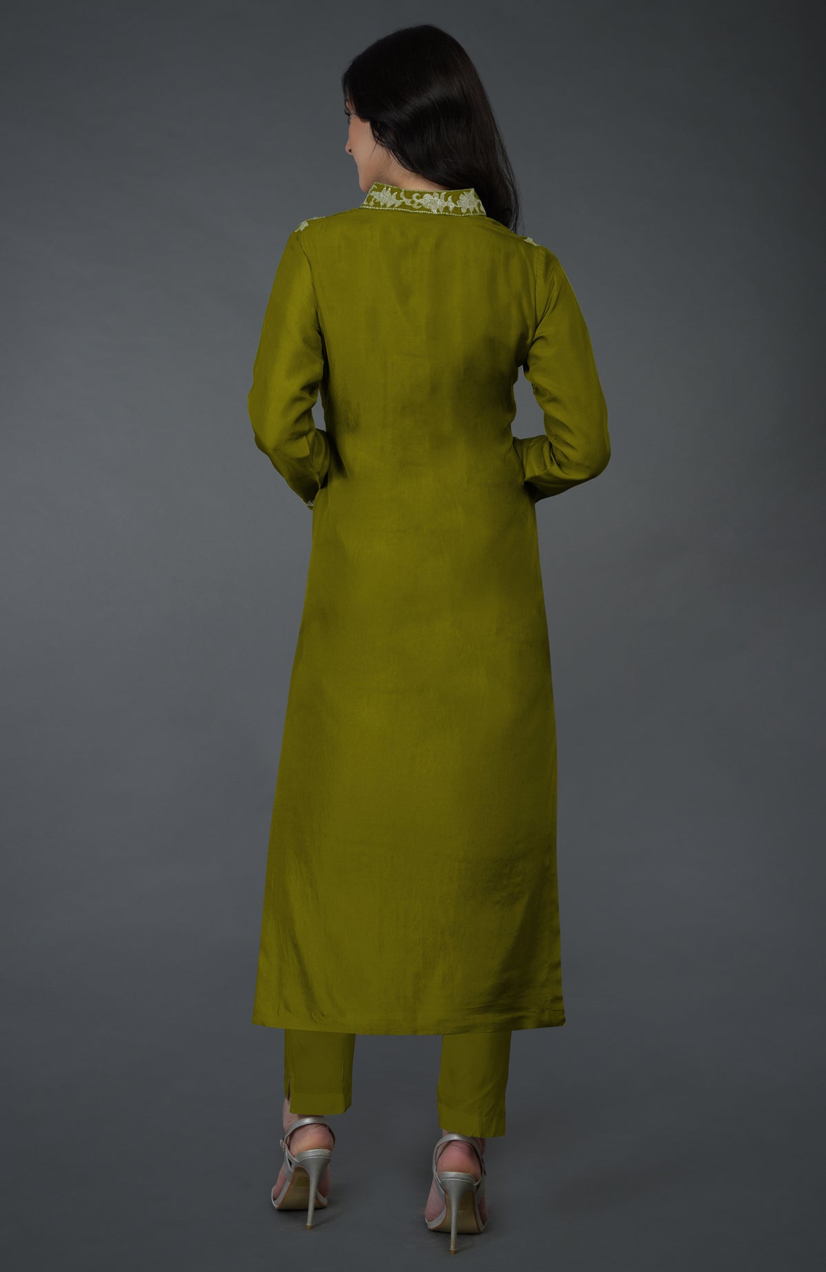 A woman from behind wears an olive Kashmiri Tilla embroidered kurta set with silver heels.