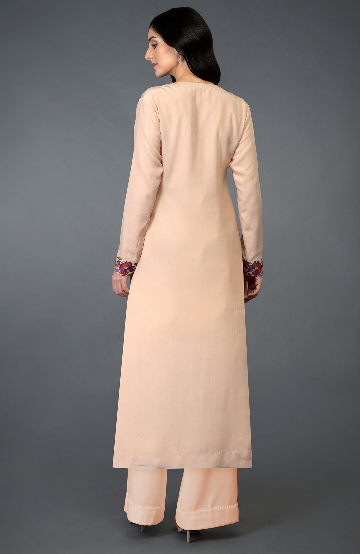 A woman from behind wears a tea rose kurta set with Kani art embroidery on the sleeves.