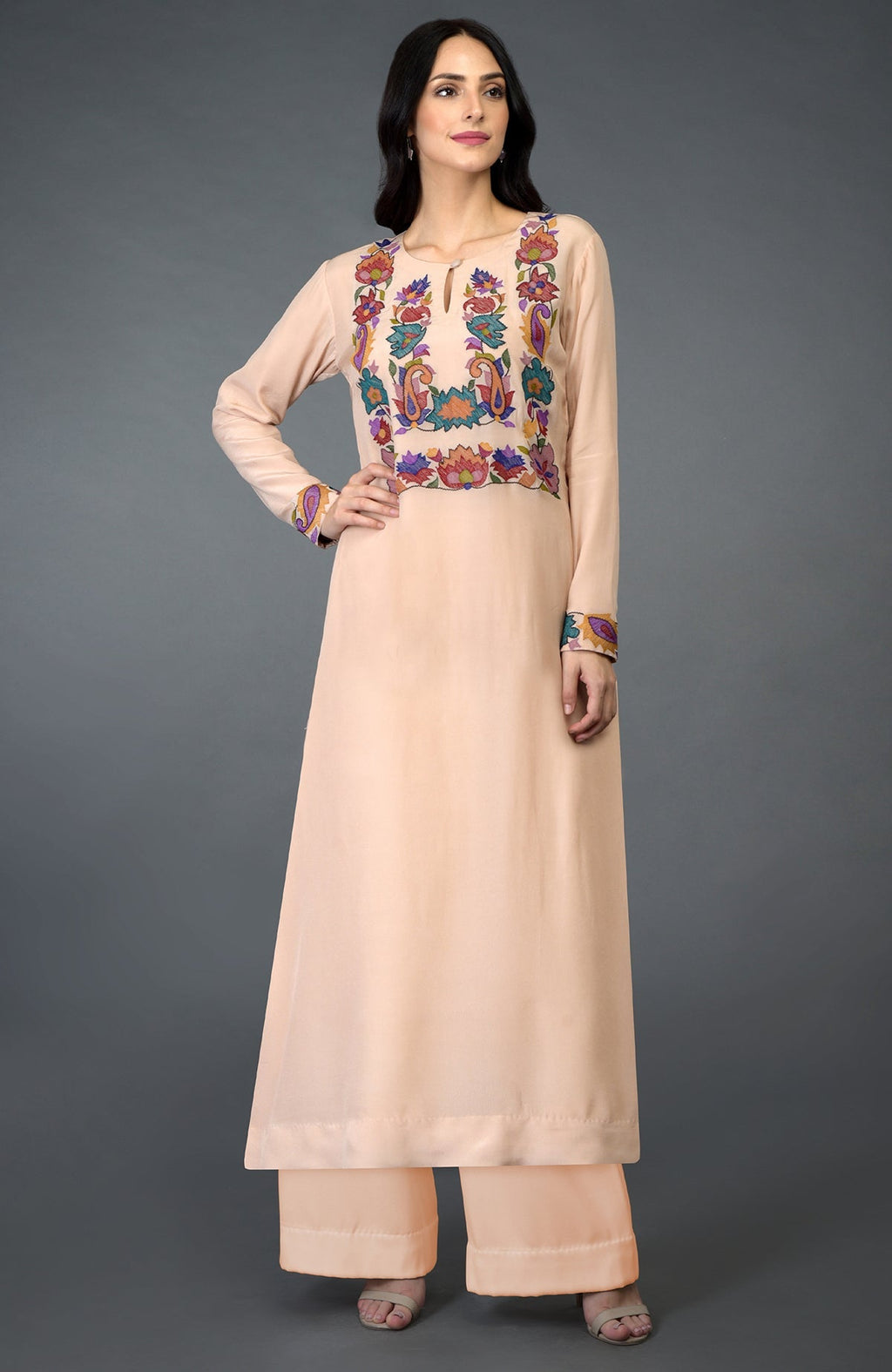 A woman models a tea rose kani art embroidered kurta set with colorful floral patterns.