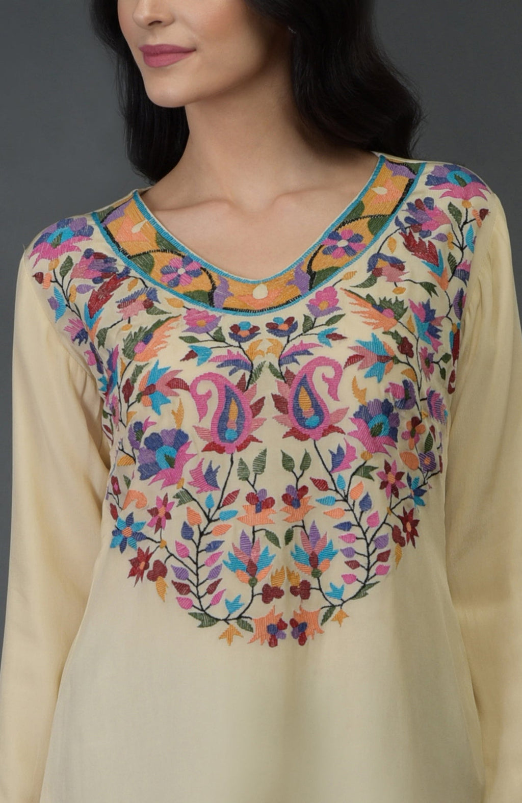 A woman models a deep cream kurta with colorful Kani art embroidery.