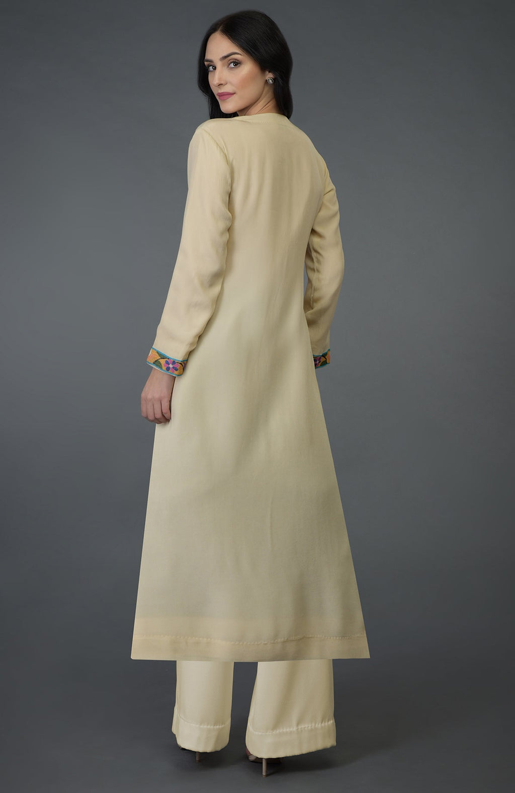A woman models a deep cream kurta set with colorful Kani art embroidery on the sleeves.