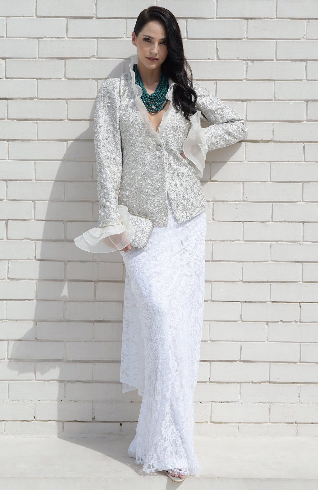 Woman in a white sequin jacket with a ruffled collar and a long white lace skirt.