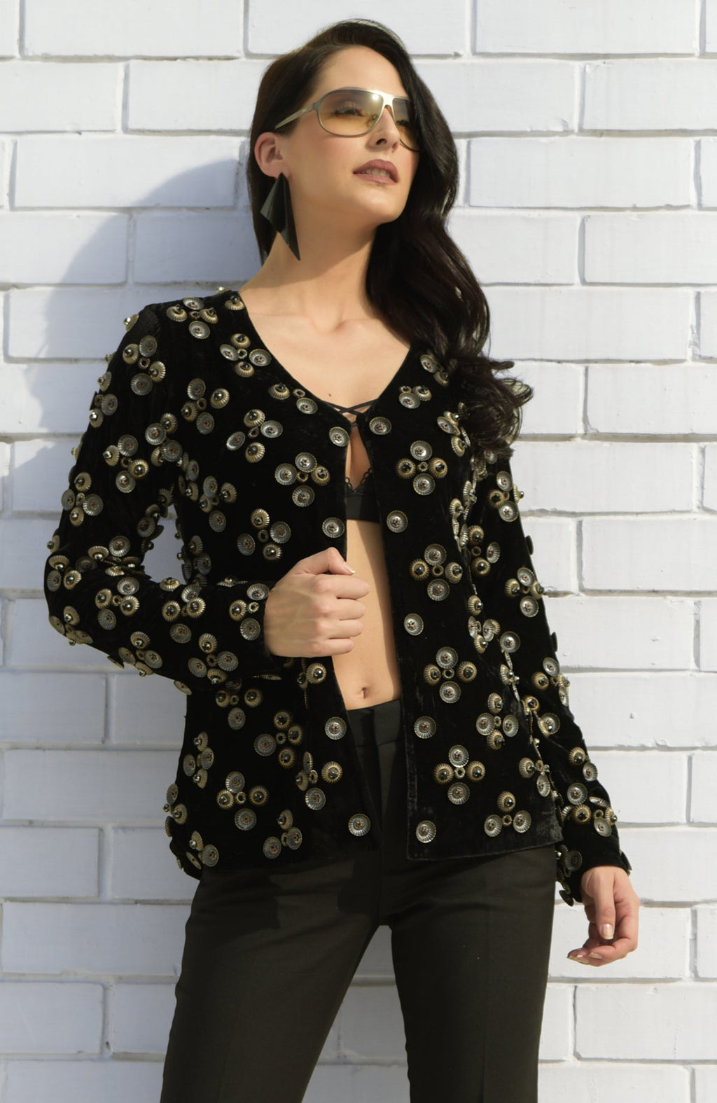 Black velvet jacket with metallic studs, worn open over a bralette and dark pants.