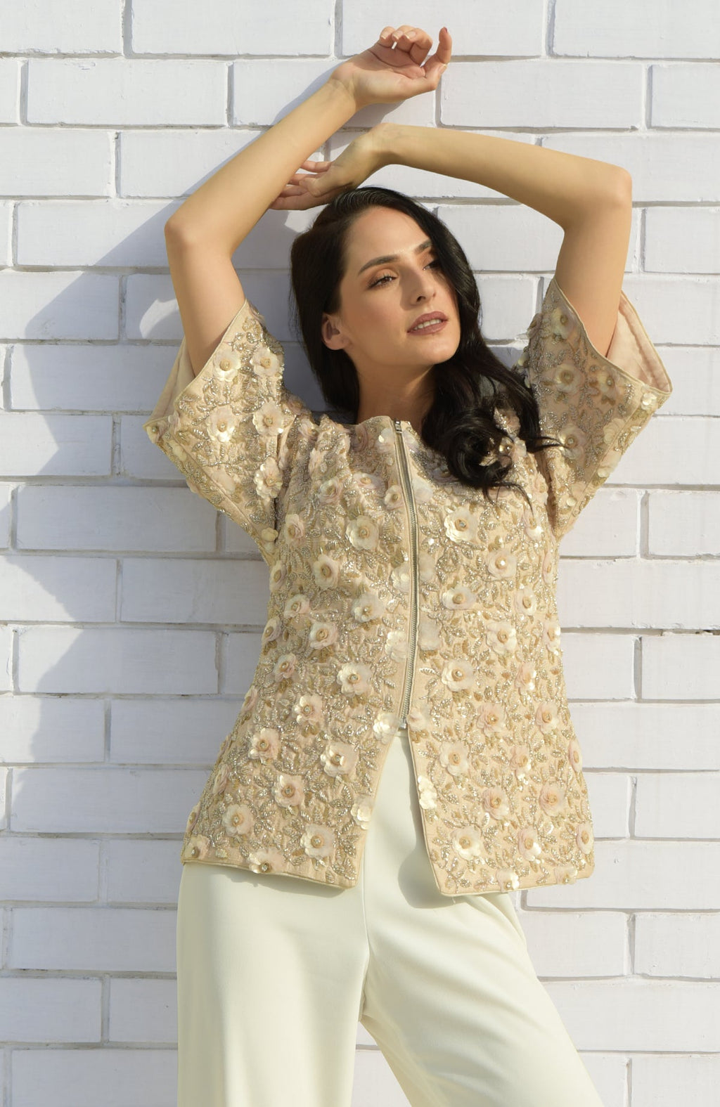 A woman models a light peach sequin and beaded hand-embroidered jacket with 3D flowers.